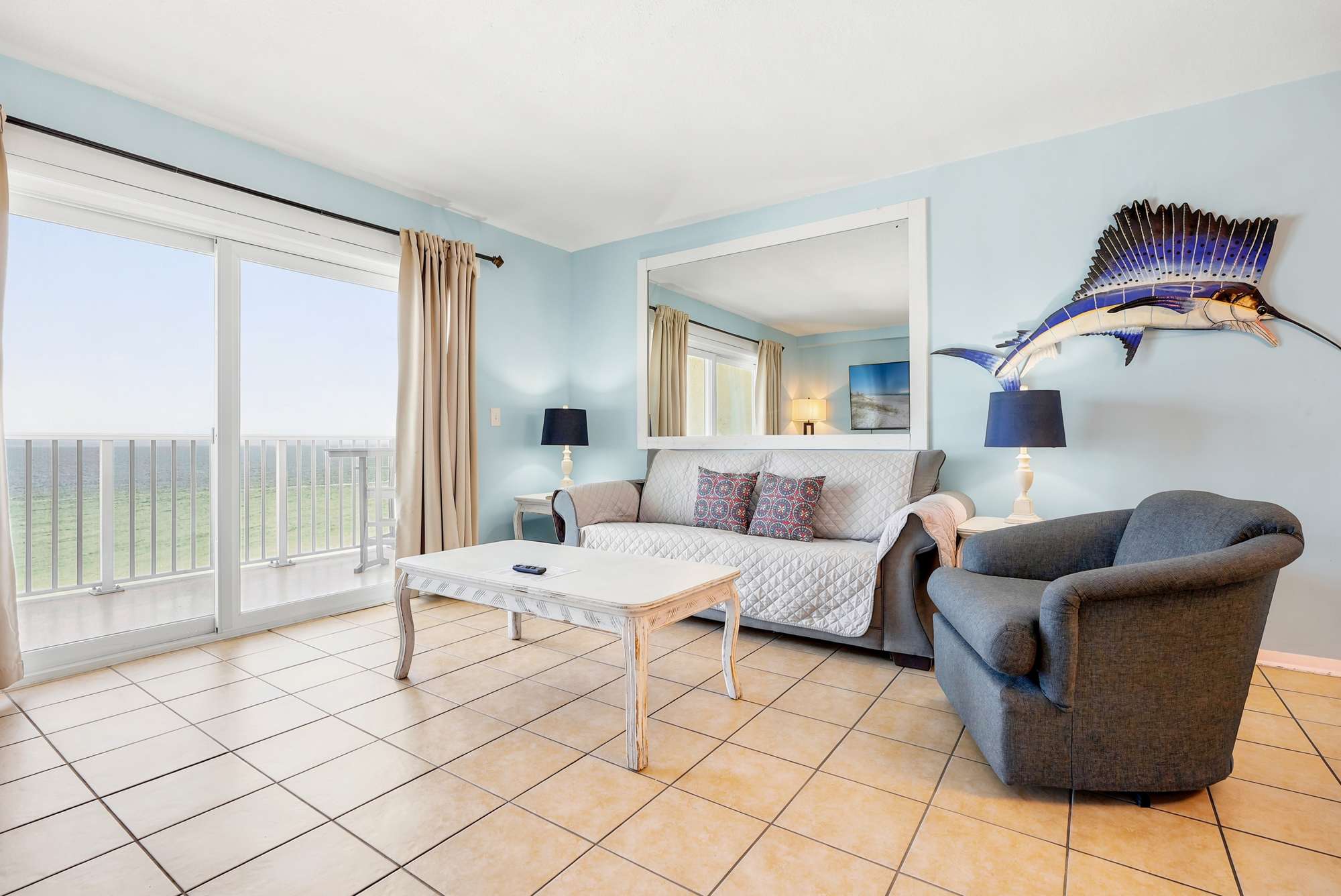 The Summit 1021 – Living room with couch, chair, coffee table, and large windows showing ocean view.