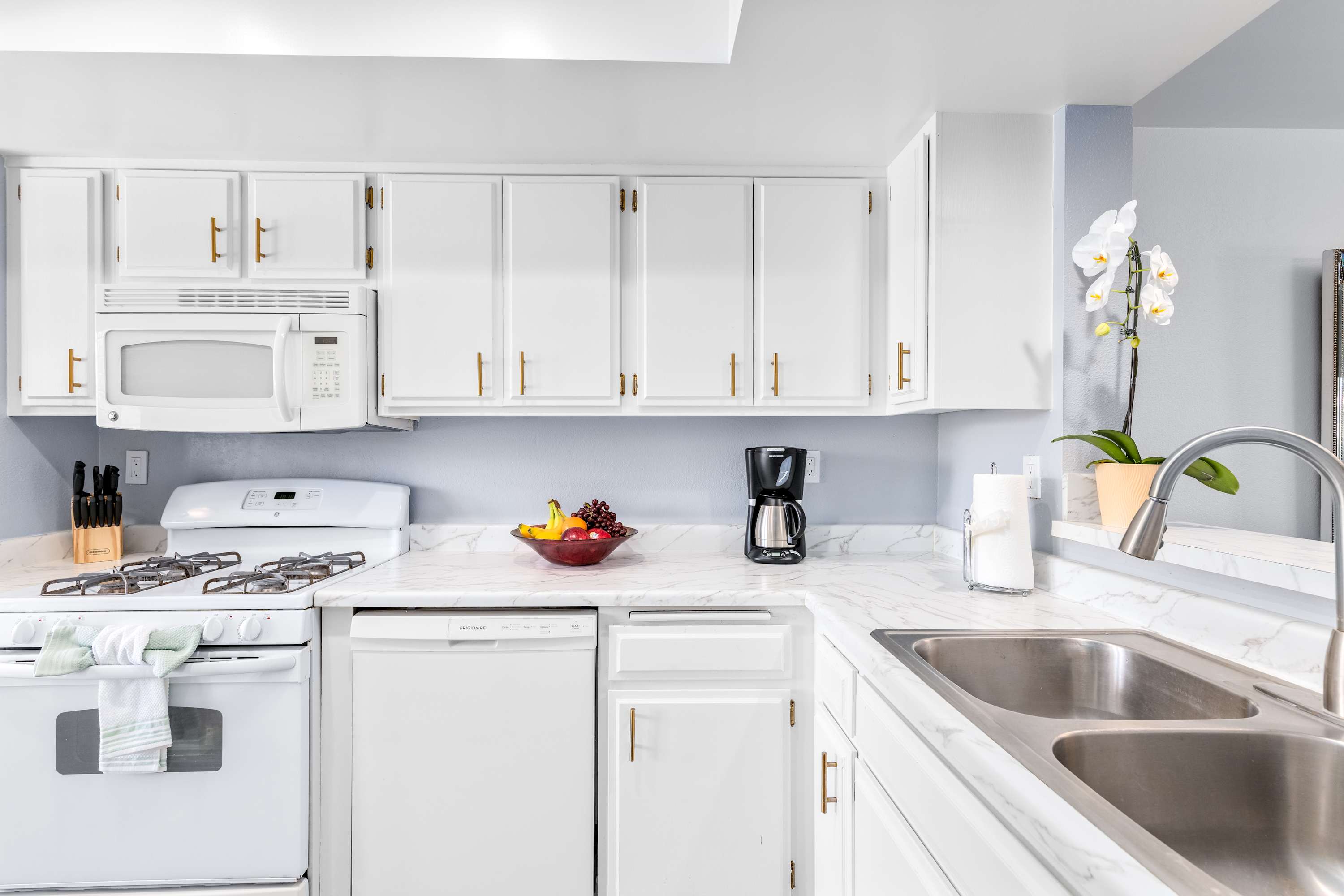 Kitchen with white cabinetry, gas range, dishwasher and sink.