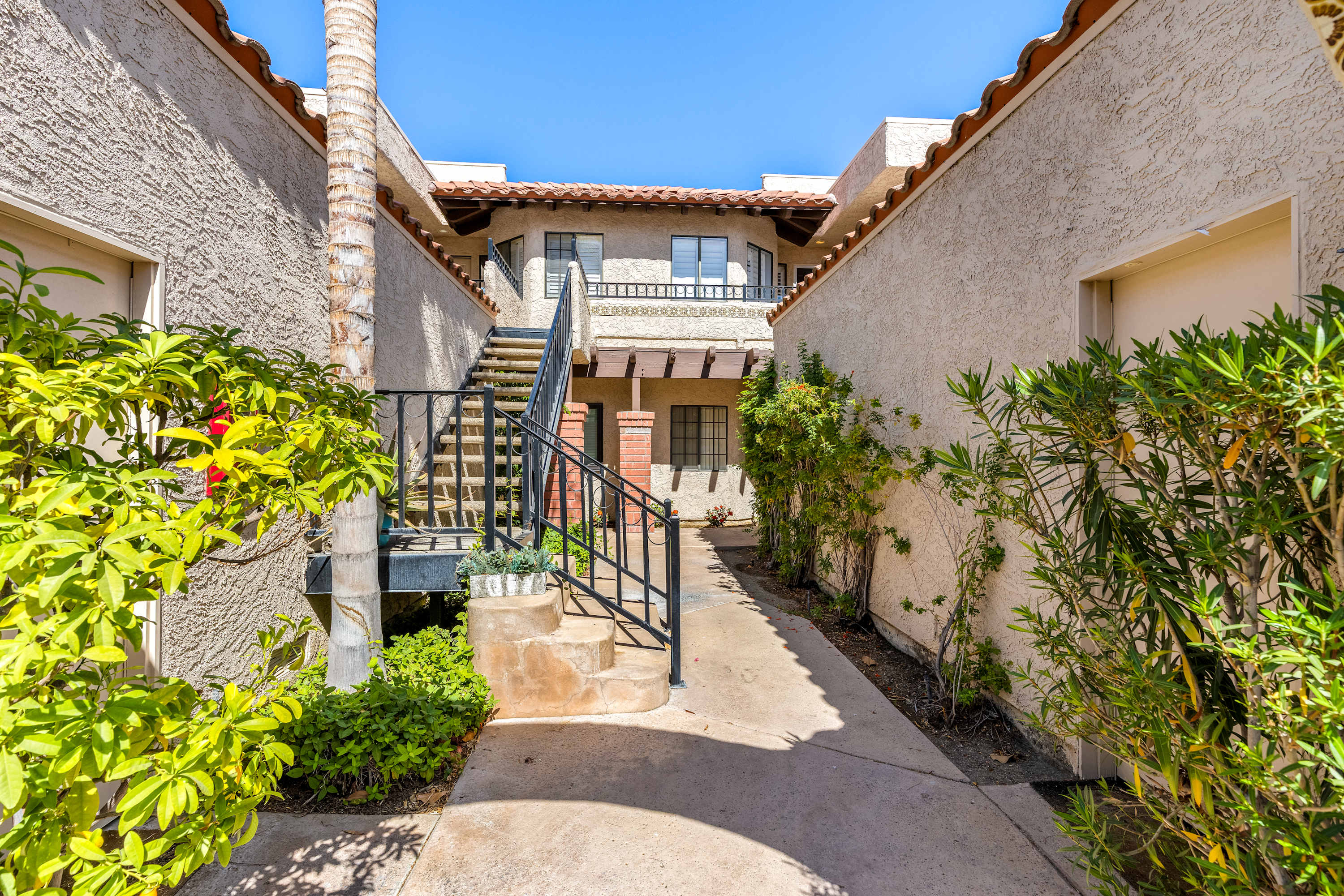 Gated entry walkway with landscaping, stairs and an overhead passage.