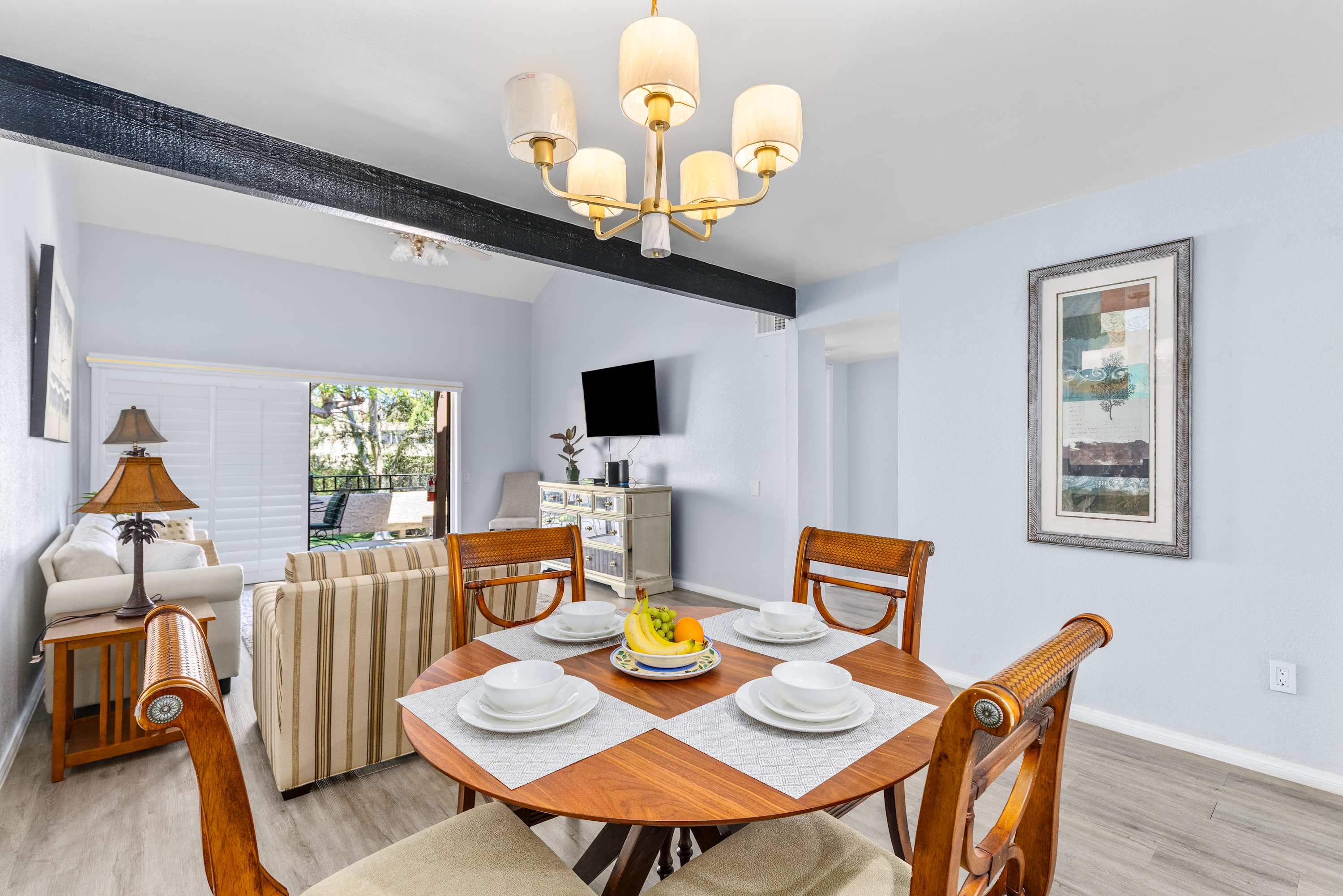 Round dining table with place settings beneath a chandelier.