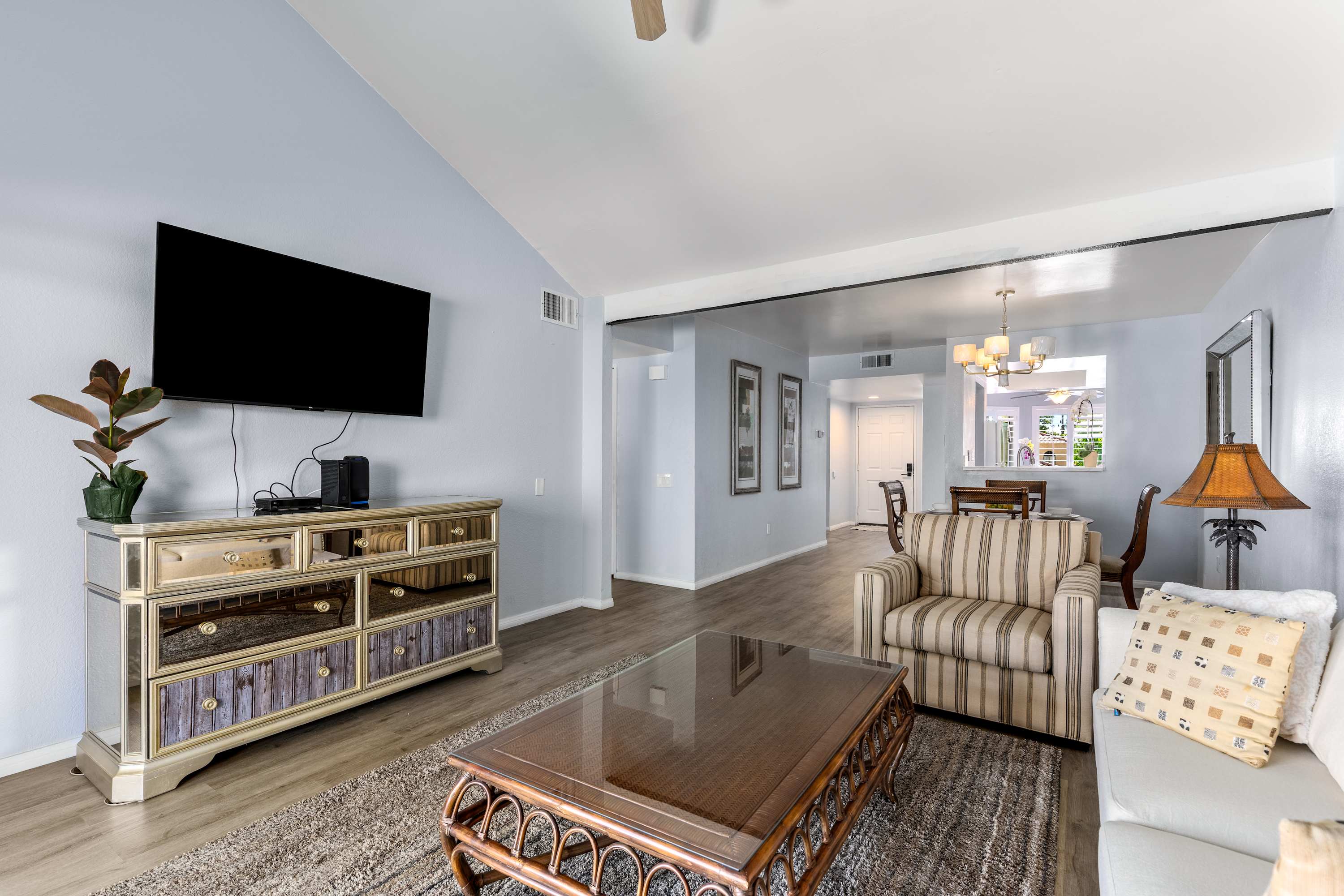 Living room view toward the TV console, seating and adjoining dining area.