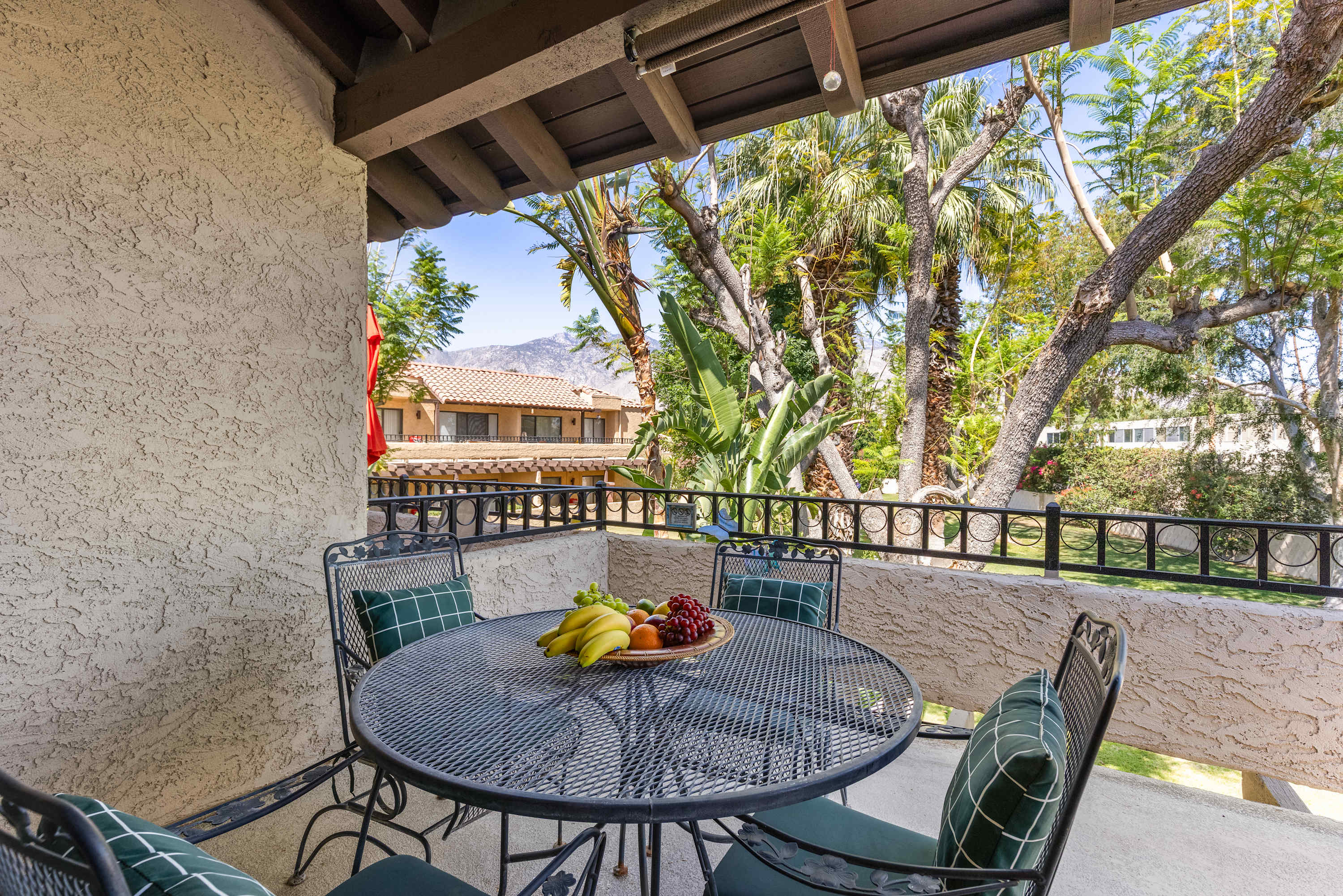 Covered balcony dining table and chairs surrounded by trees.