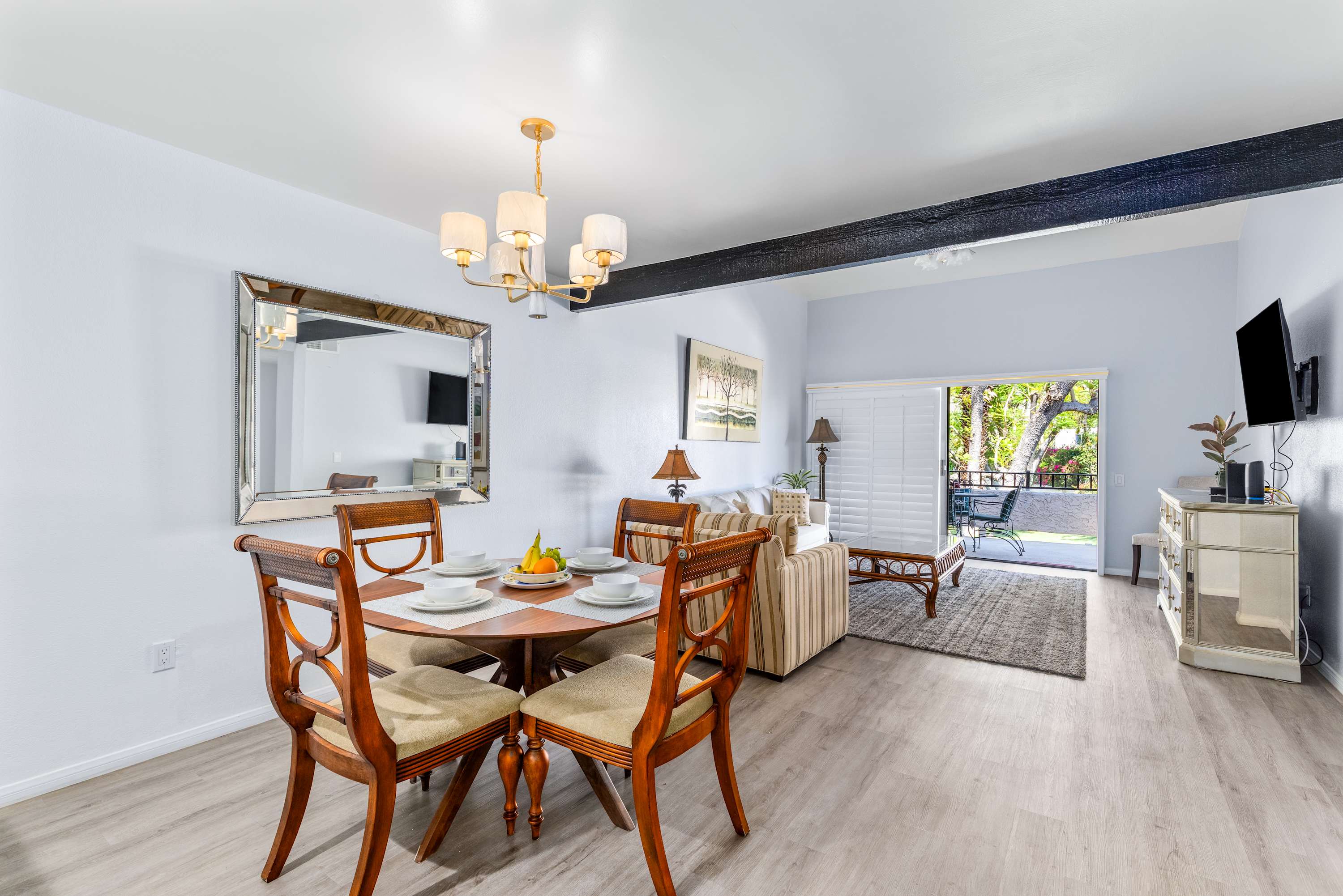 Dining table with wood chairs and chandelier beside the open living area.