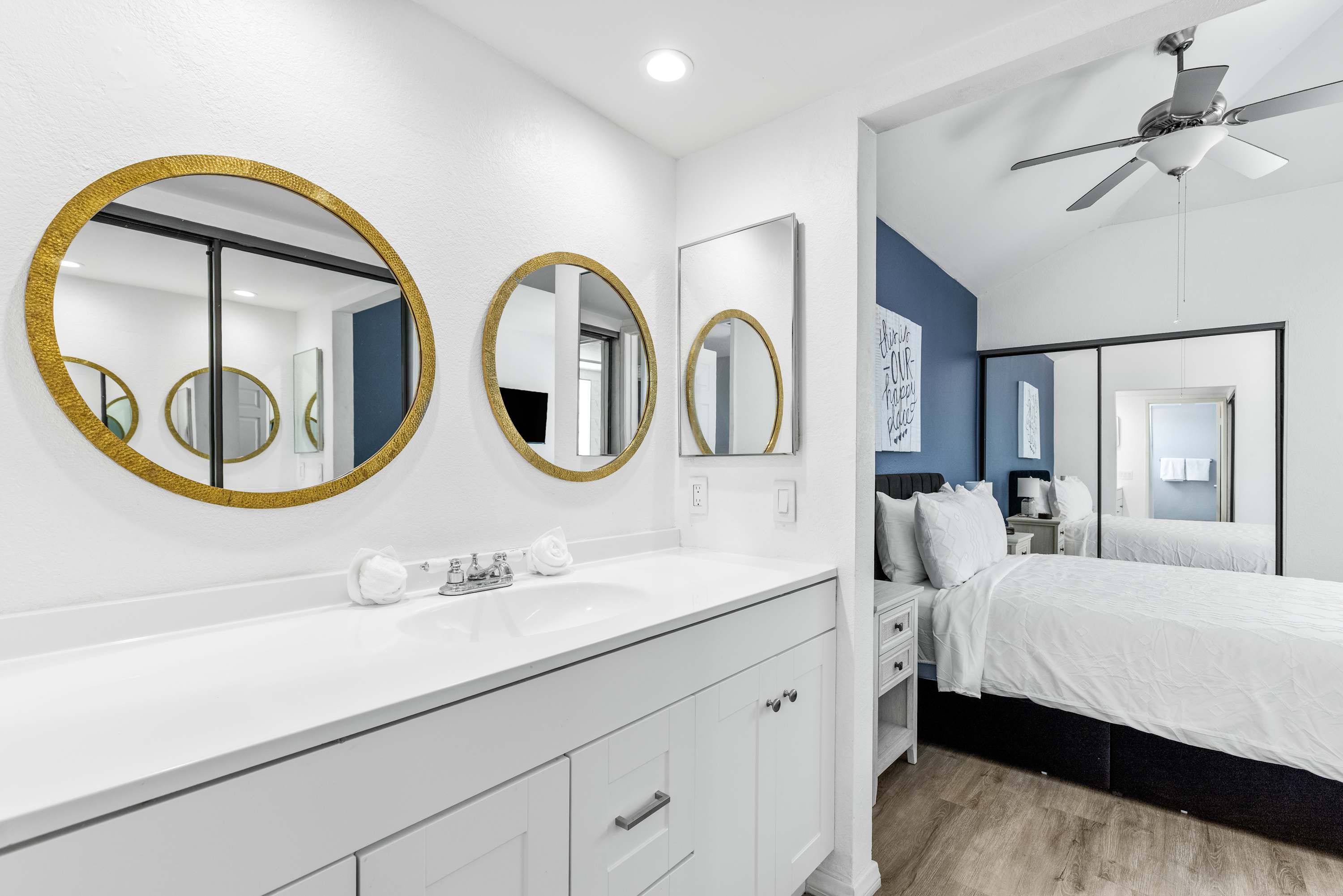 Bathroom double vanity with round gold-framed mirrors beside the bedroom.