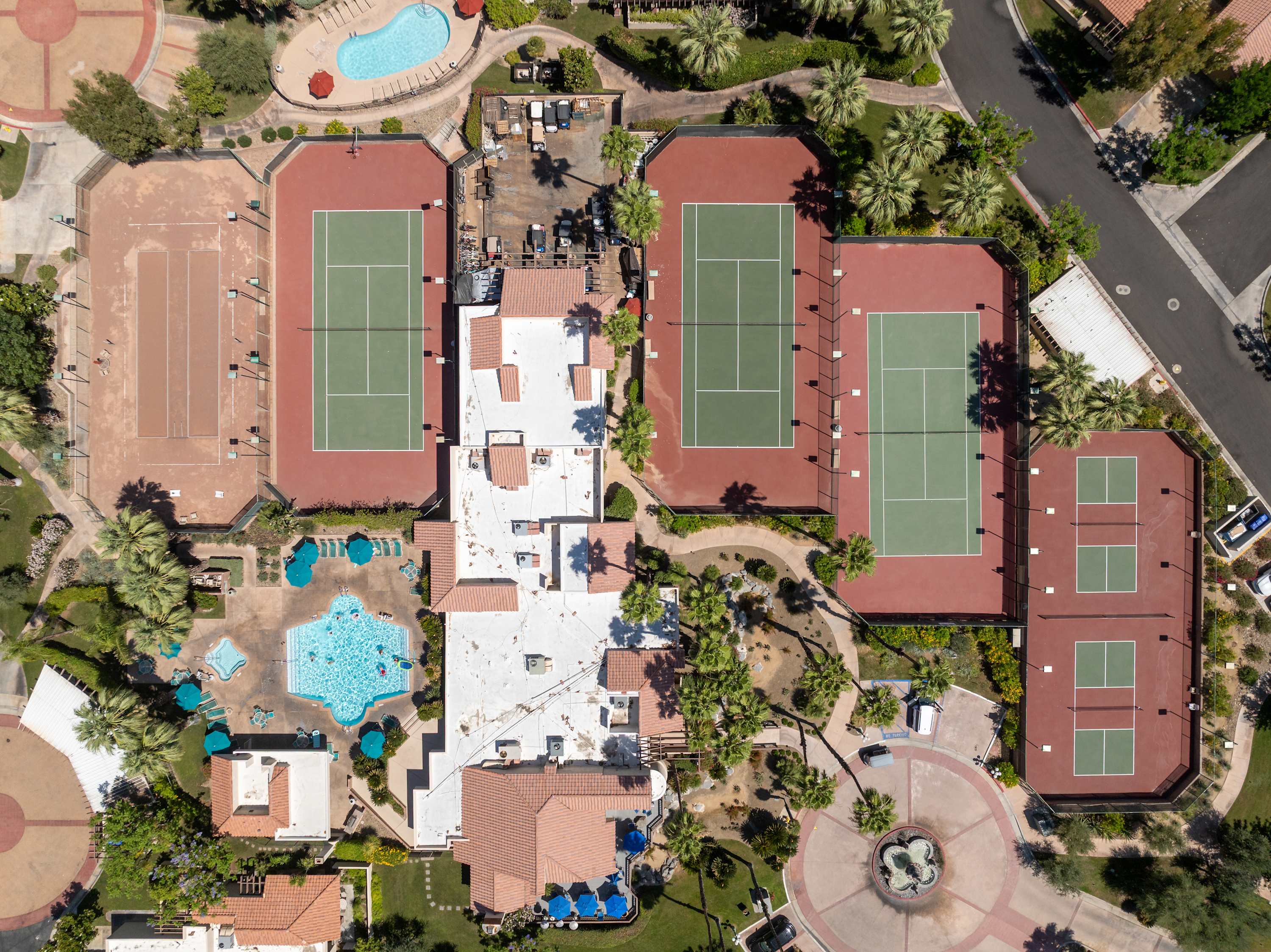 Overhead view of tennis courts, pools, walkways and landscaped grounds.