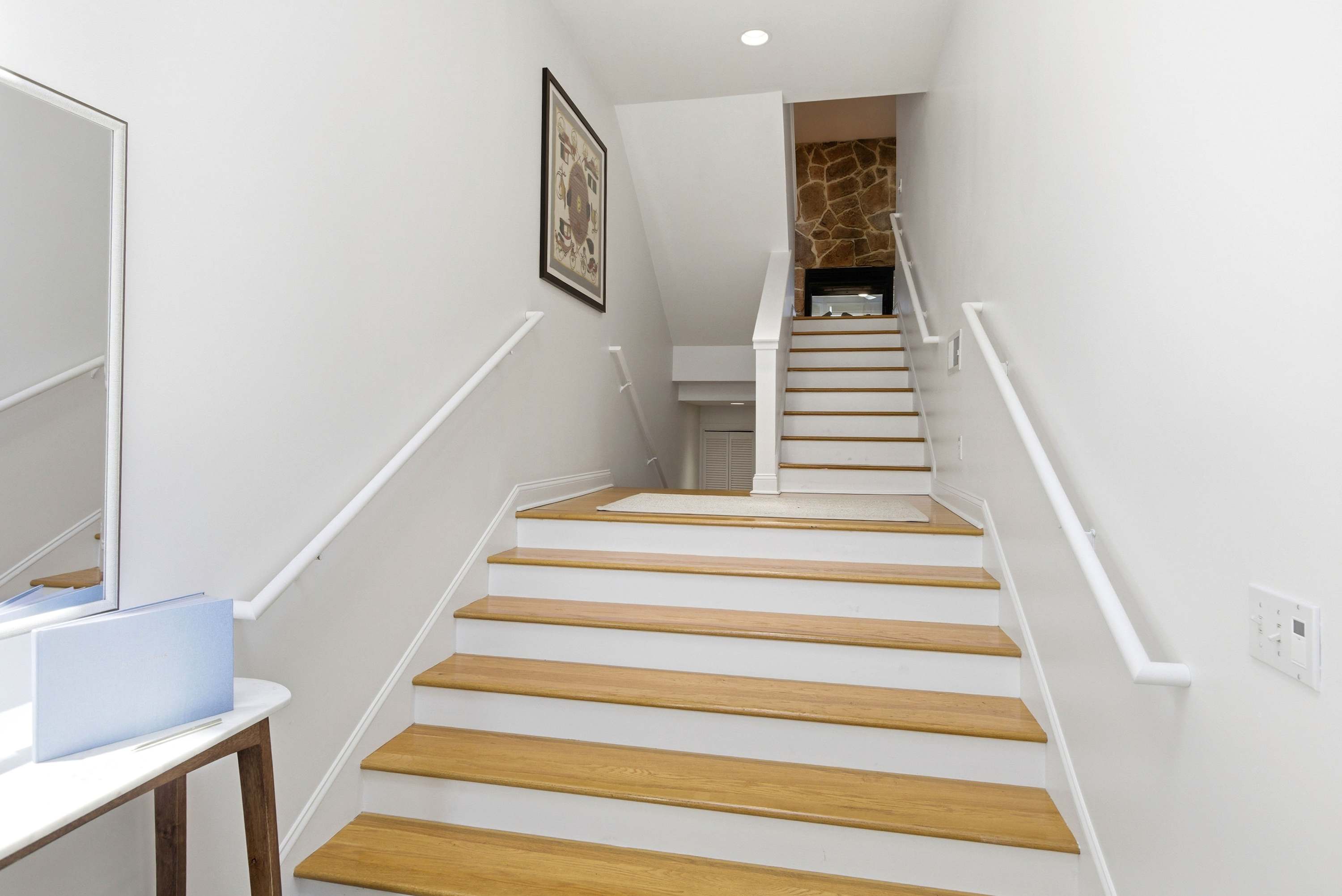 Light-filled entry staircase with warm hardwood treads and clean white risers leads you straight to the heart of the home.