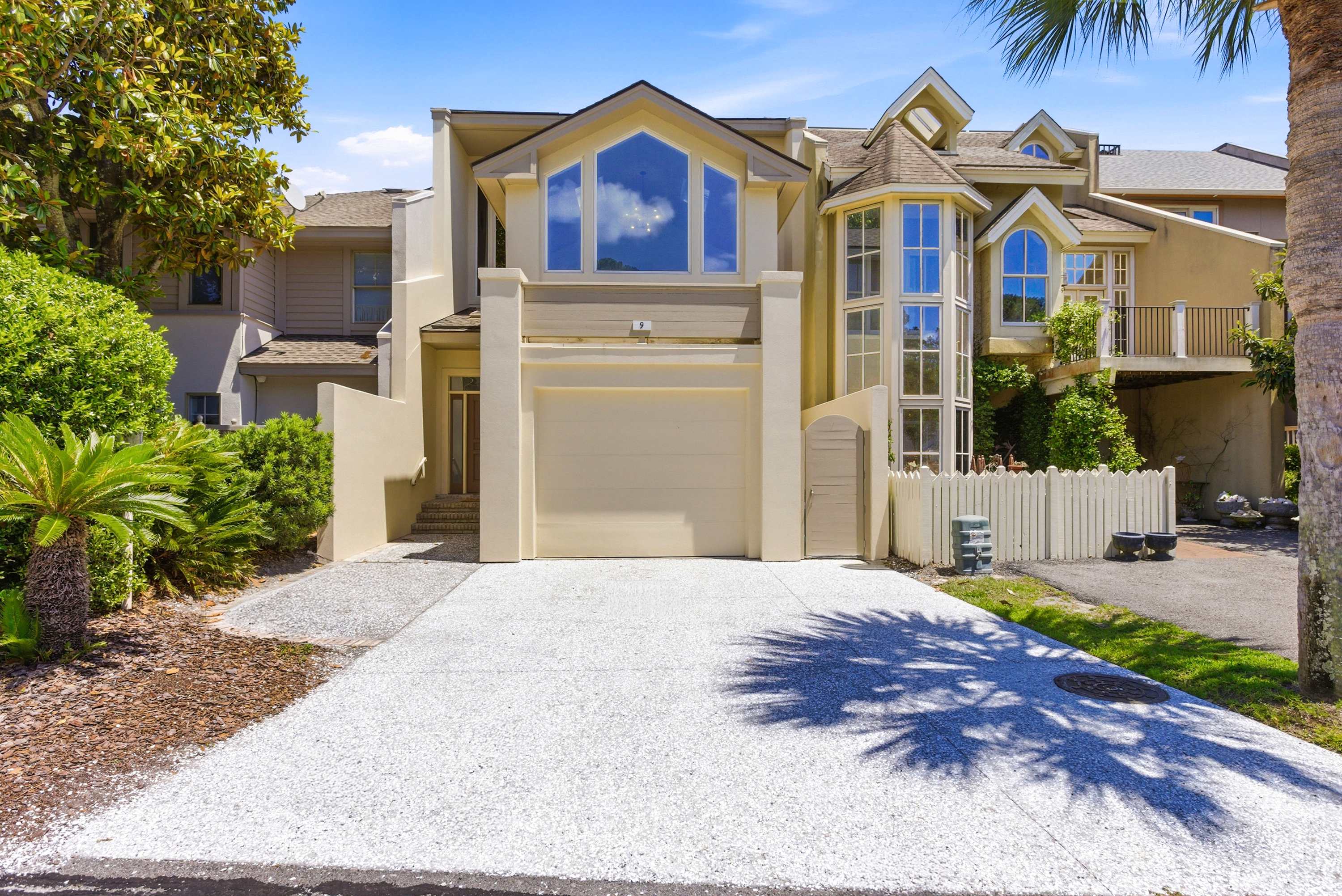 Soaring two-story windows and lush coastal landscaping set the tone for the luxury retreat that awaits inside.