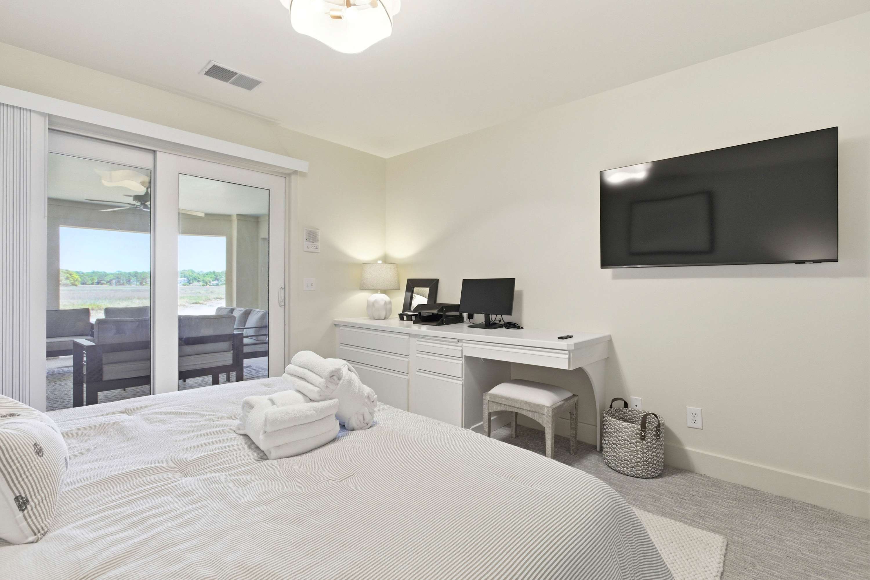 King suite featuring a dedicated vanity station, wall-mounted TV, and sliding doors opening directly to the waterfront deck.