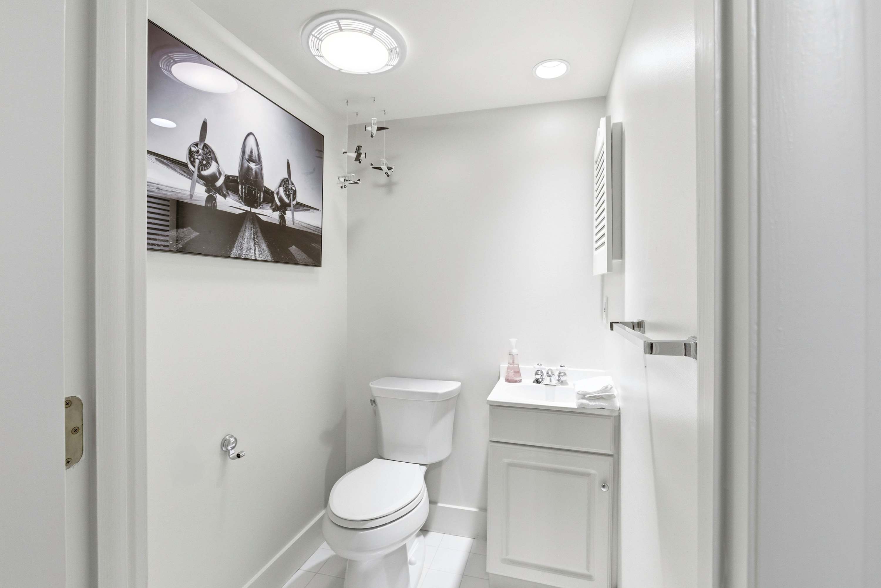 Whimsical aviation-themed powder room with vintage propeller artwork and a charming model plane mobile.