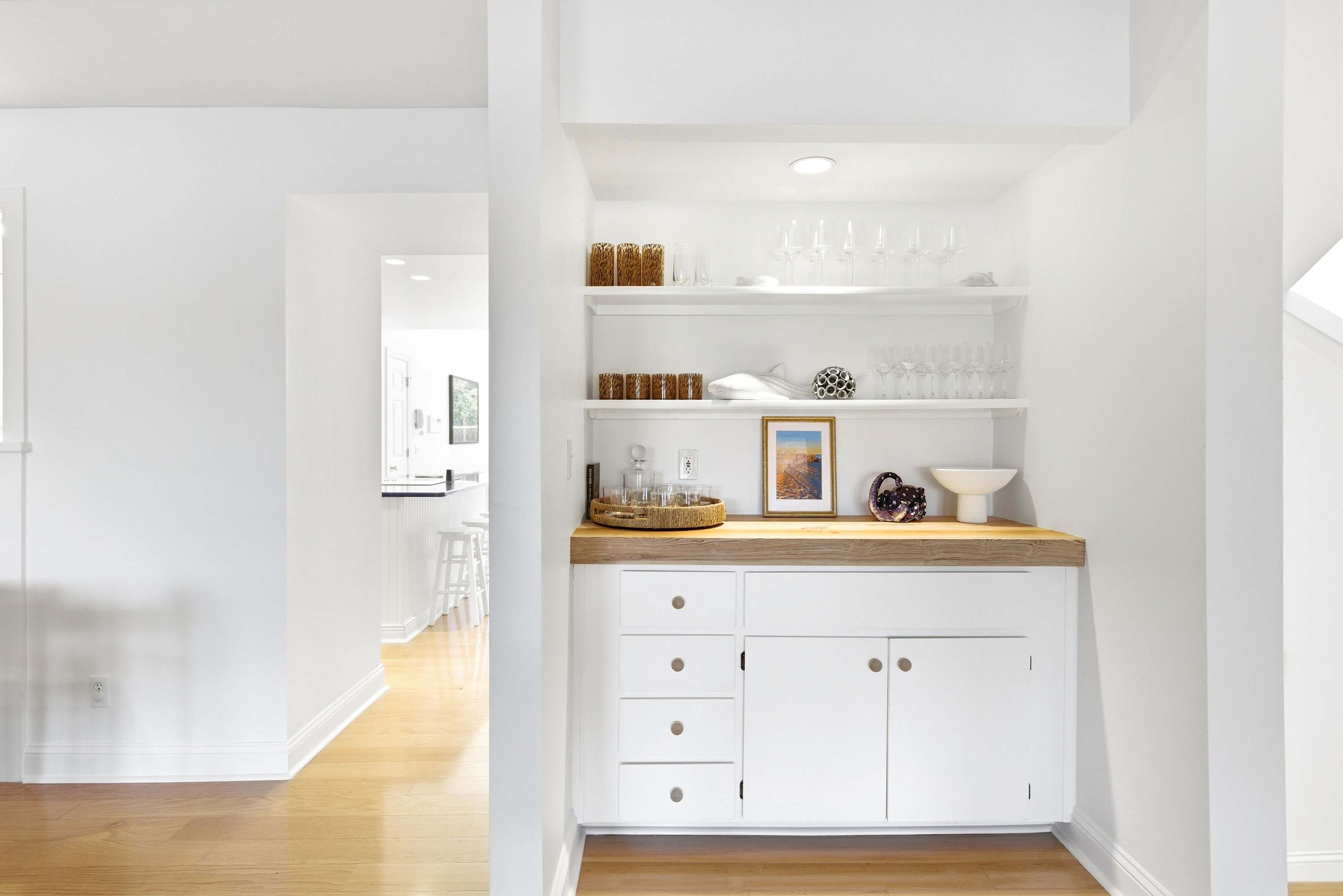 Built-in butler's bar with butcher block counter and open shelving stocked with glassware, just steps from the main living area.