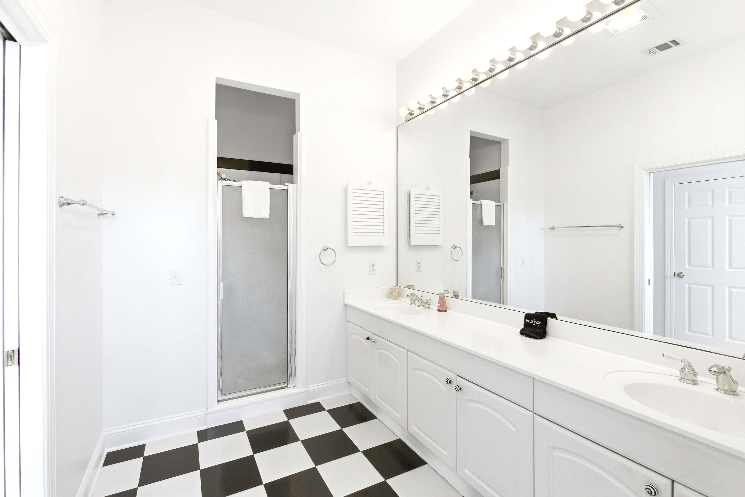 Primary en-suite entry with striking black-and-white checkerboard tile, full-length vanity, and natural light from a skylight.