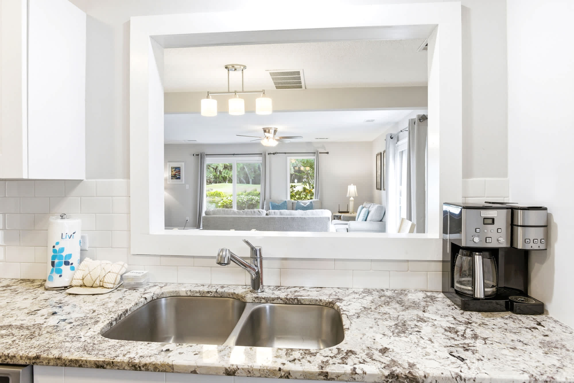 A wide pass-through window opens the kitchen to the living area, keeping the chef in the conversation while natural light flows through.