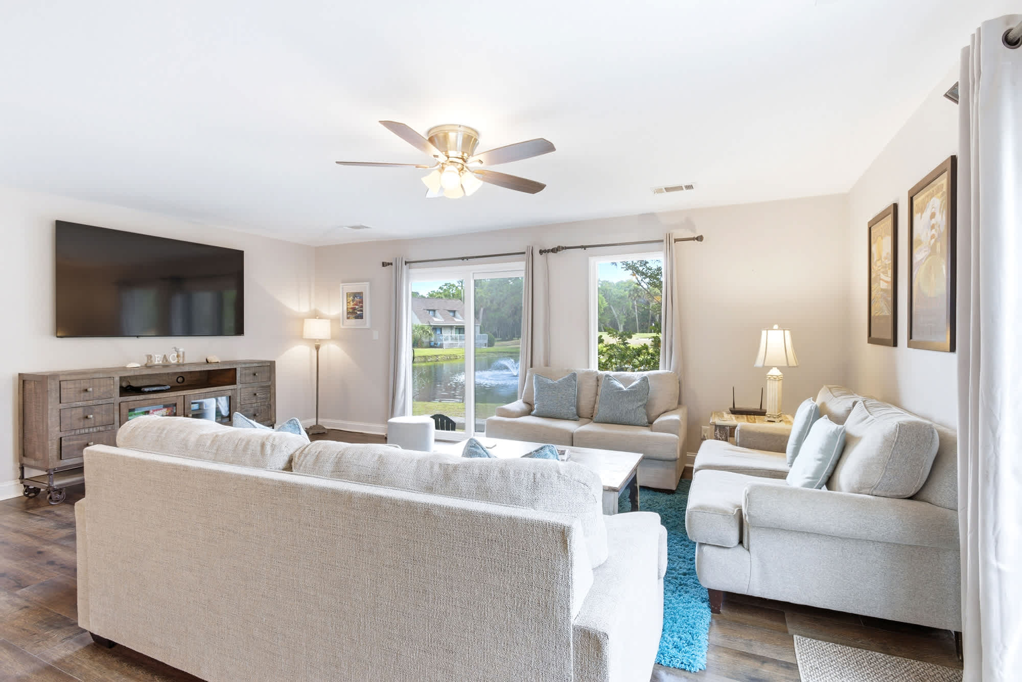 Large wall-mounted TV, ample seating, and a peaceful pond-and-fountain view through the windows make this the ultimate rainy-day retreat.