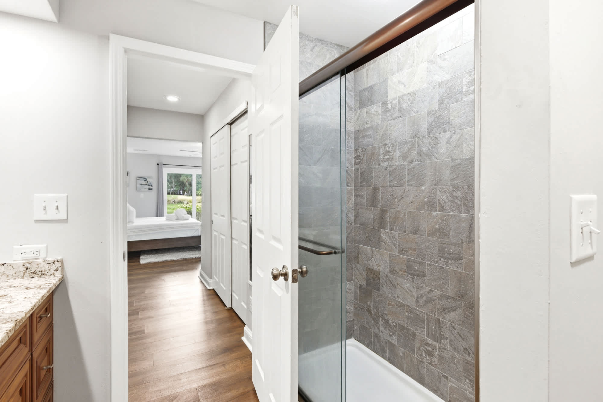 Large walk-in shower with floor-to-ceiling gray stone tile and a glass enclosure — everything you need after a day at the beach.