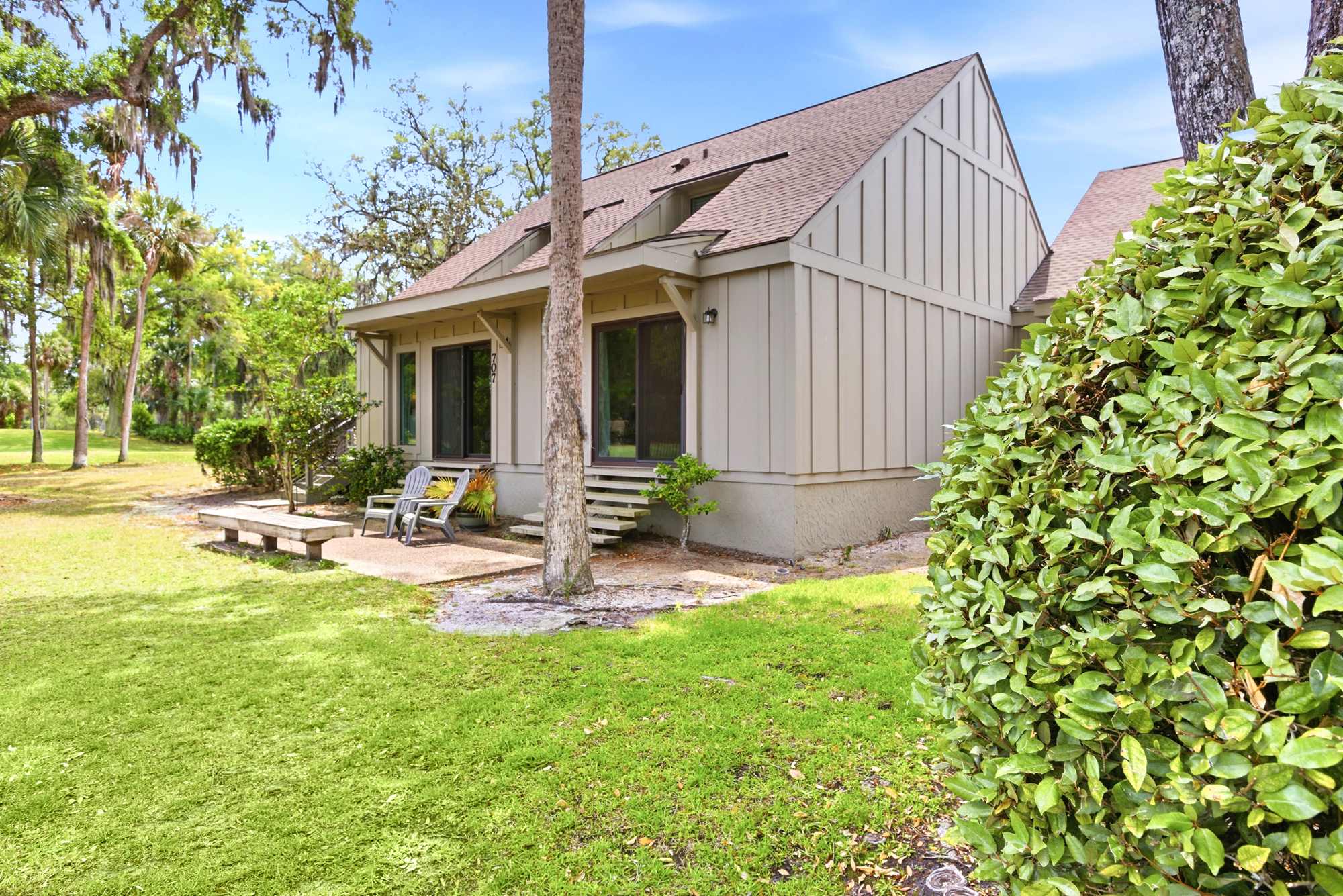 Mature palms, live oaks, and manicured greenery surround 707 Queen's Grant, creating a private, nature-filled escape close to everything.