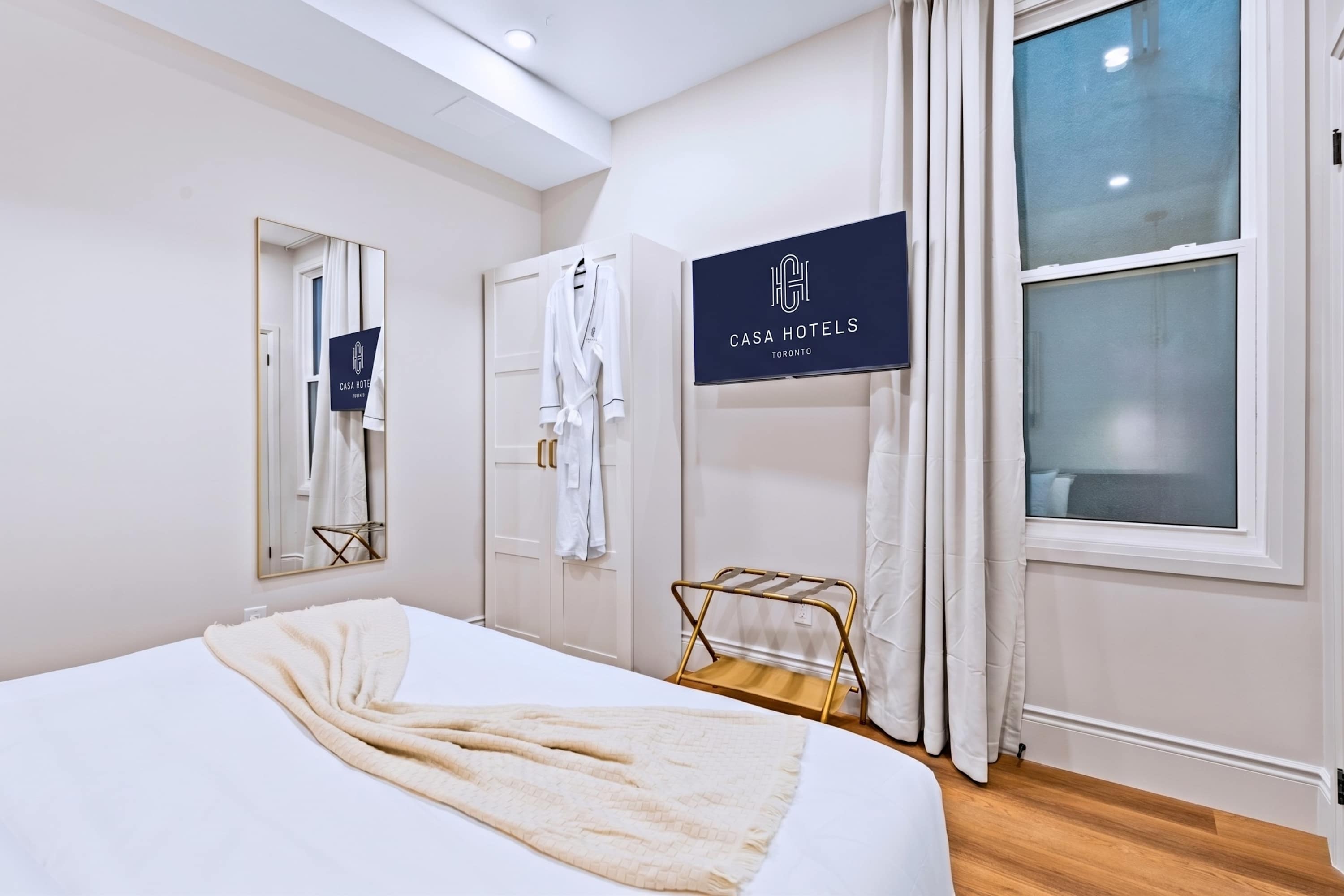 Comfortable bedroom with natural light, a mirror, a towel, and a bathrobe provided.