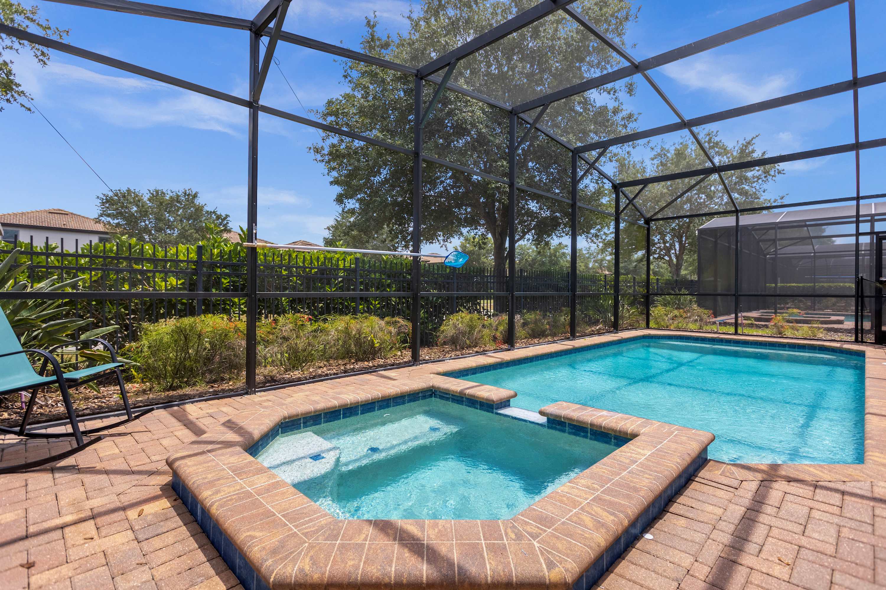 Relax in your private screened pool and hot tub, surrounded by lush greenery and bathed in sunlight—your perfect retreat.