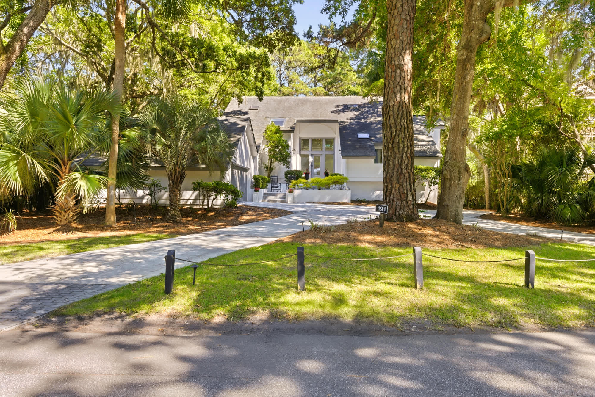 The charming white exterior emerges from a lush tree canopy, hinting at the serene retreat waiting inside.