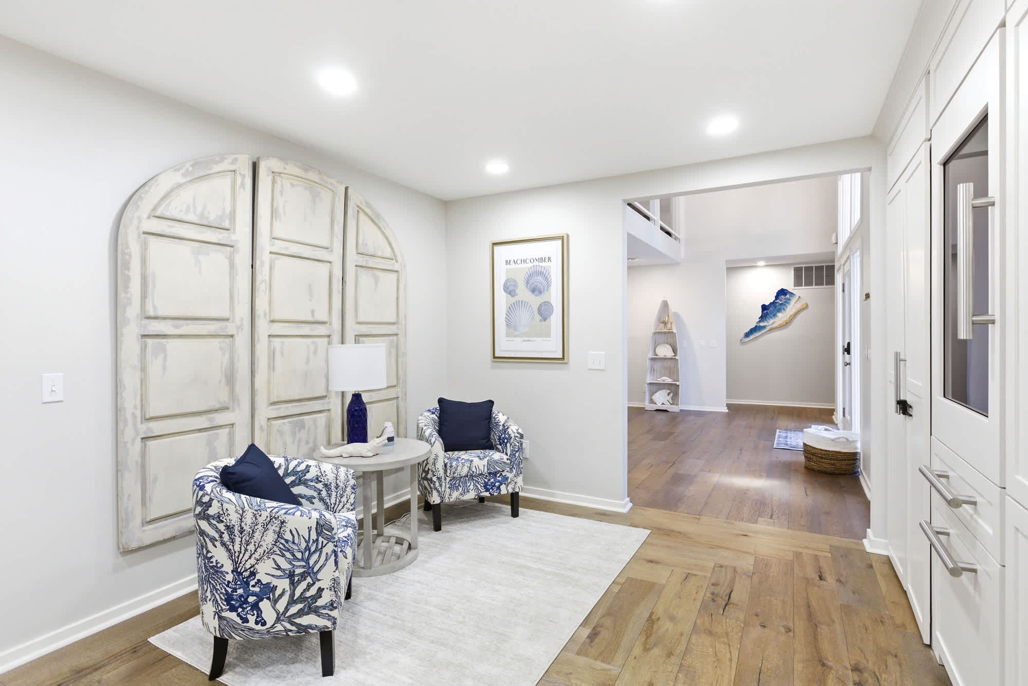 Distressed arched door wall panels, blue-and-white coral print armchairs, and shell print art create an artful, coastal-chic welcome the moment you step inside.