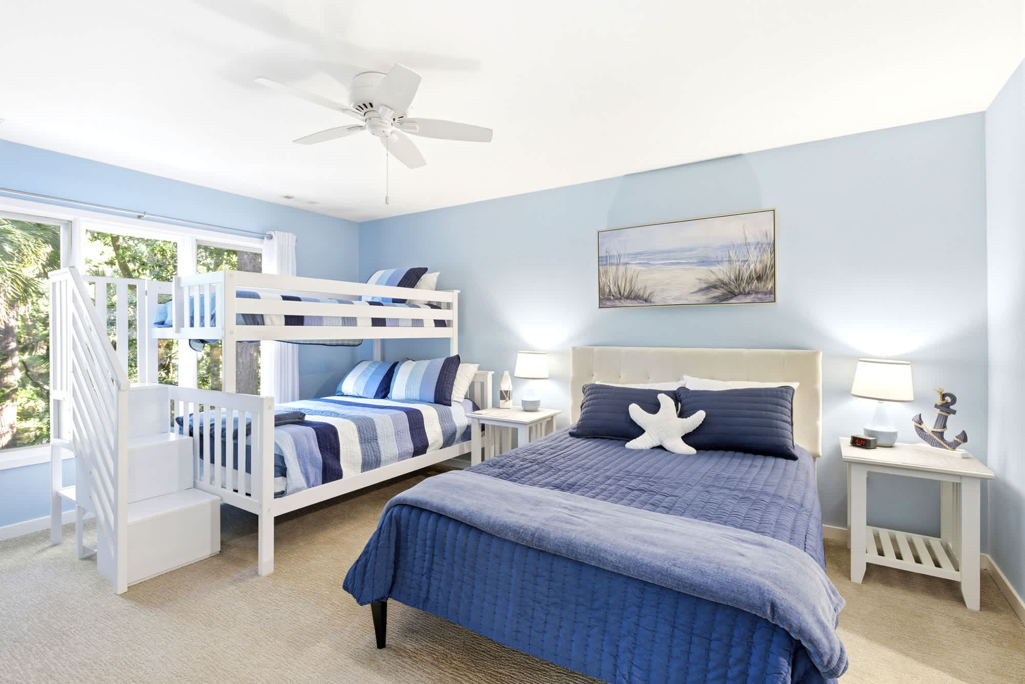 Sky-blue walls, a white full/twin bunk with stairs, a double bed, navy anchor decor, starfish pillows, and beach art make this room a hit with guests of all ages.