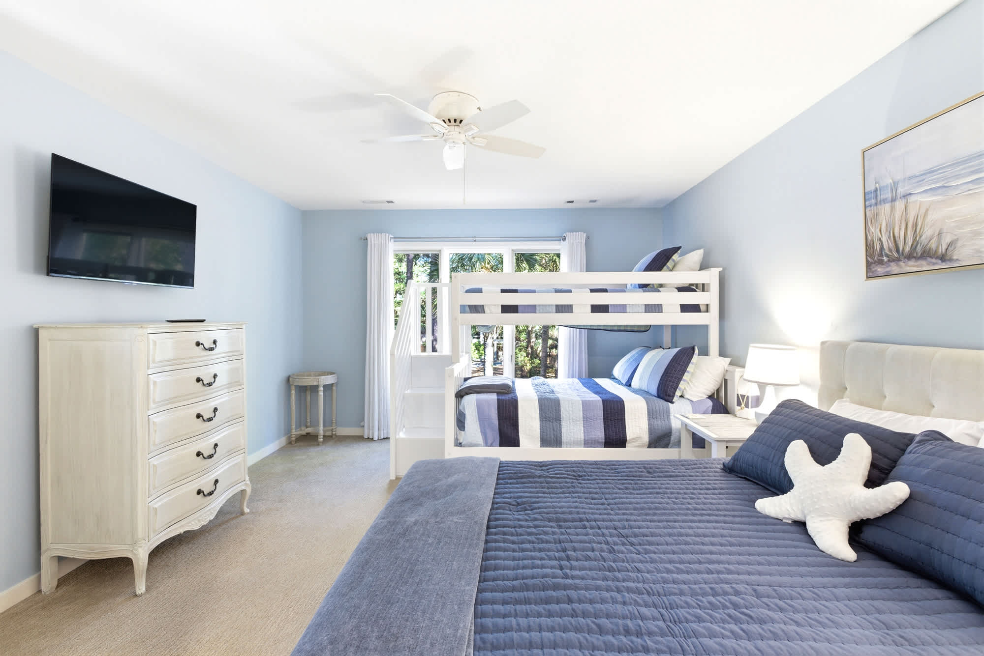 This versatile bedroom fits a queen plus a bunk set, a TV dresser, and a ceiling fan — perfect for families or groups needing extra sleep space.