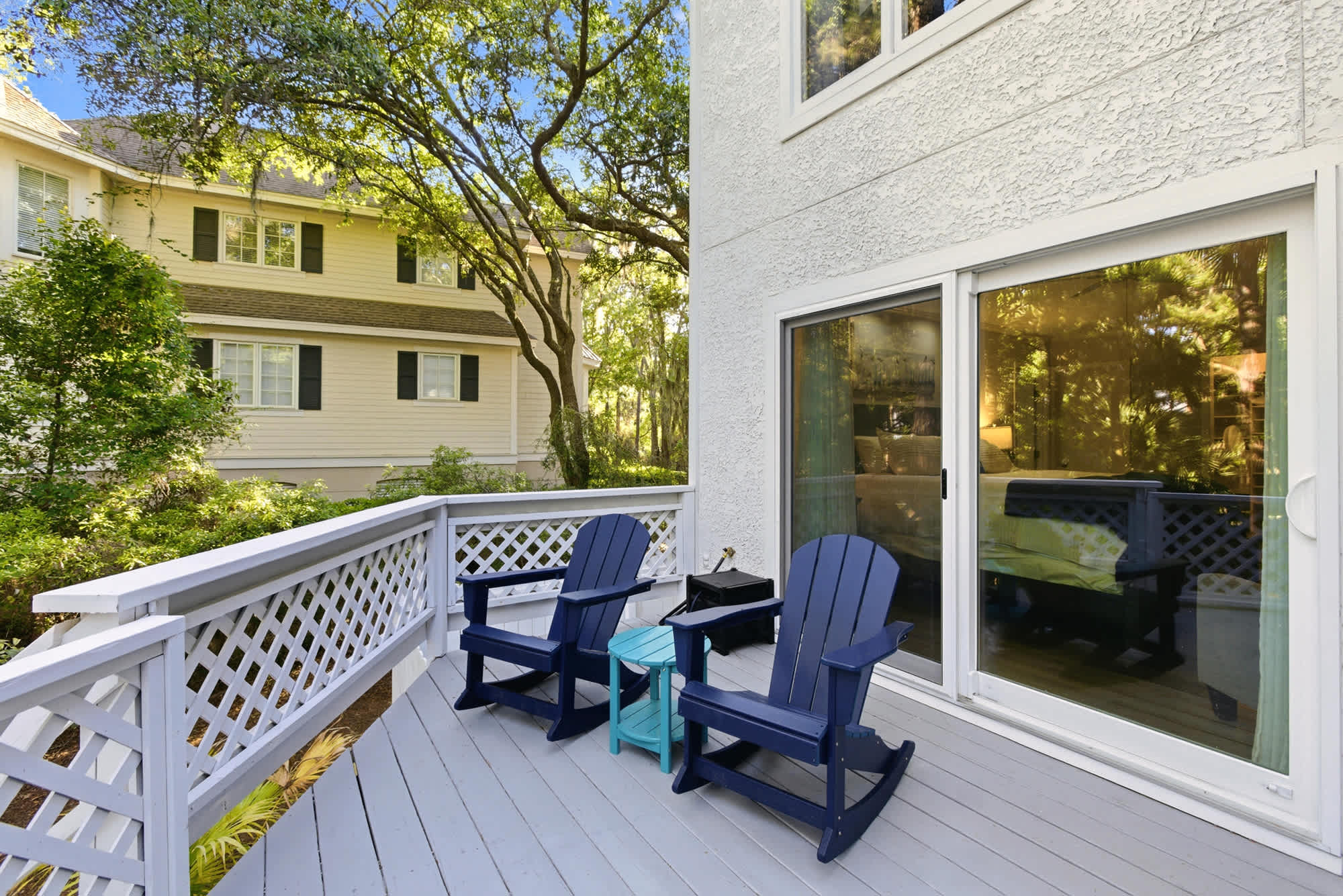 Two navy Adirondack rockers and a teal side table on the primary suite's private balcony — the perfect perch to start every morning.
