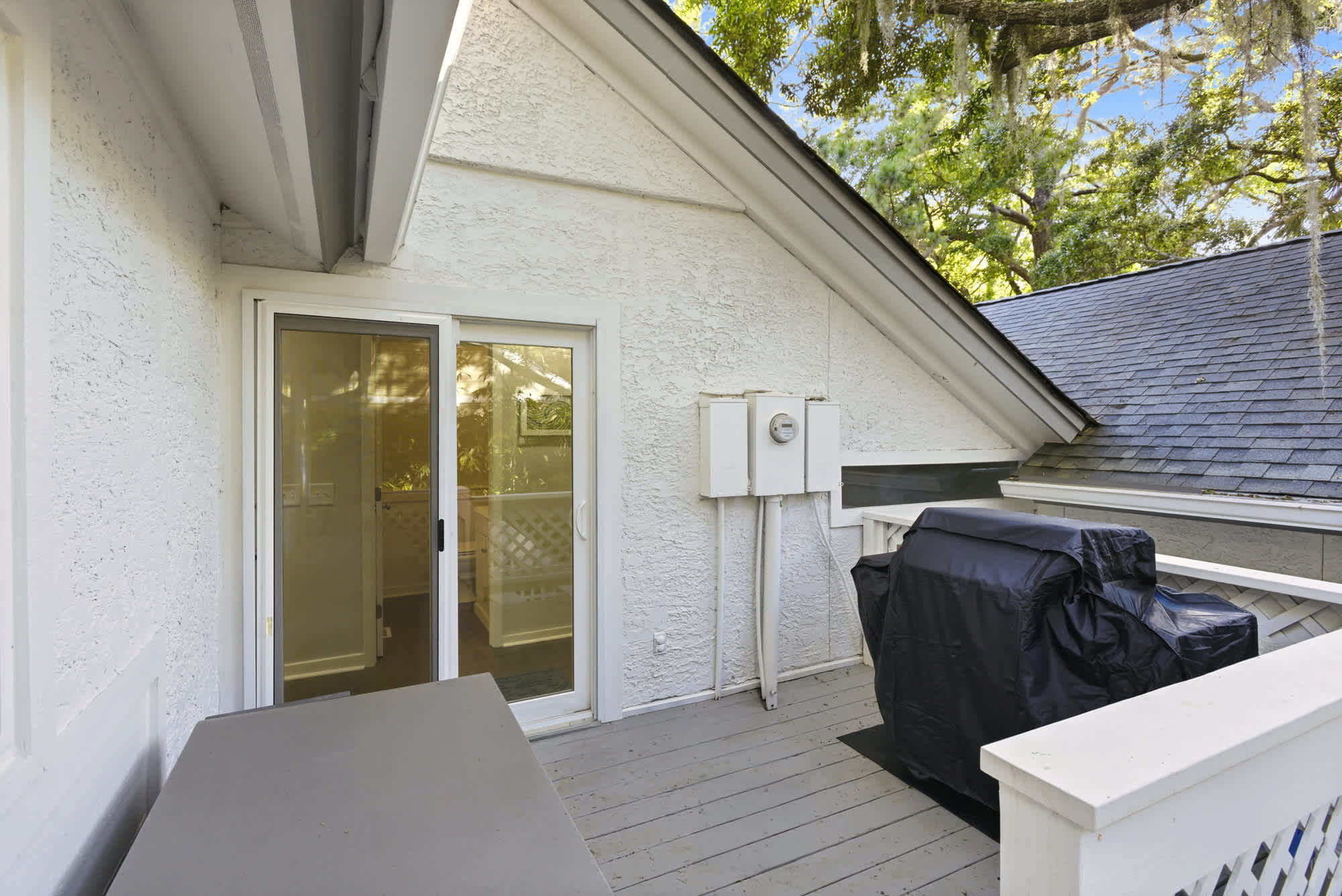 A covered grilling deck with a gas grill, outdoor table, and a canopy of Spanish moss overhead — everything you need for an effortless cookout.