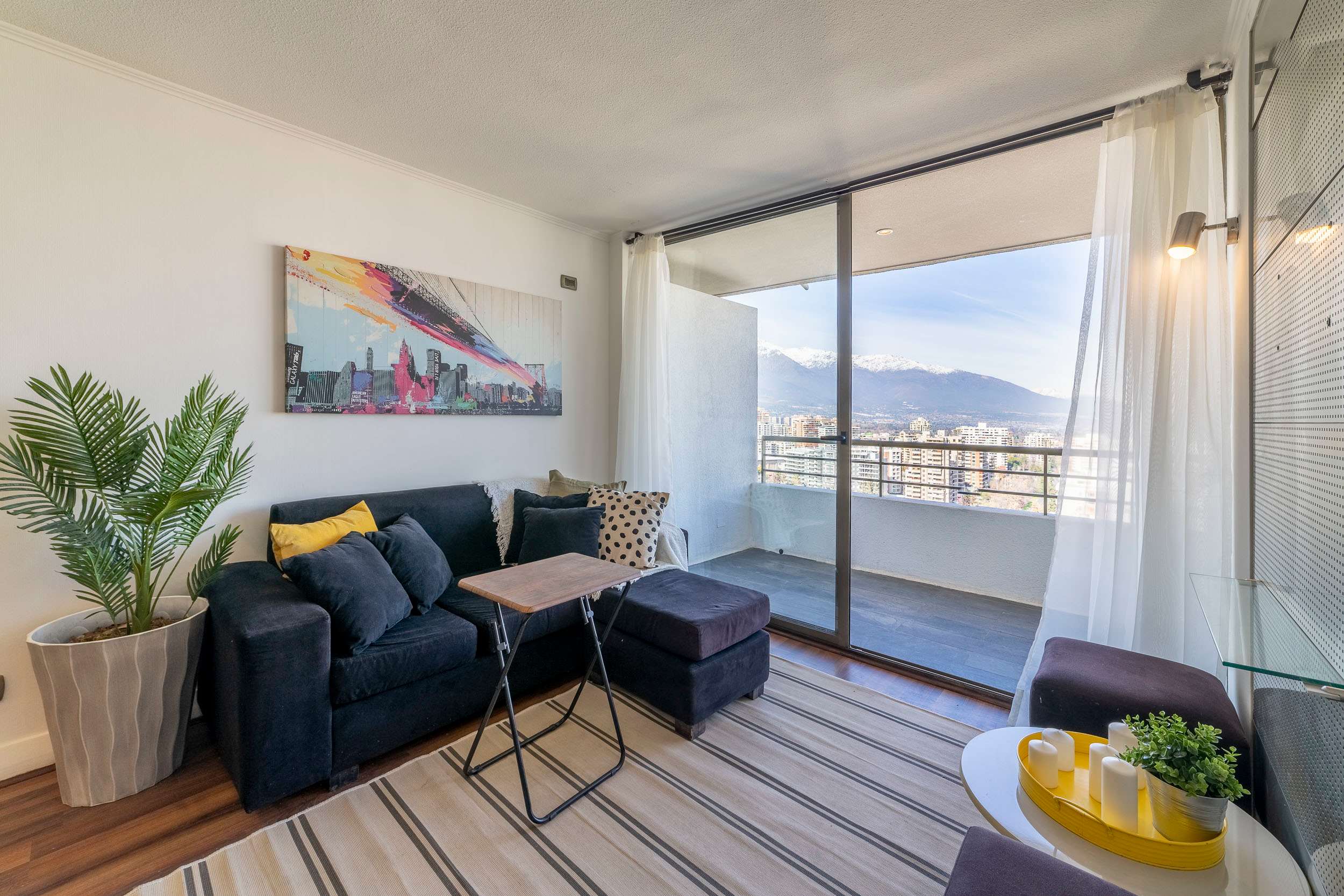 Relax in a cozy living room with breathtaking city and mountain views, perfect for unwinding after a day of exploring Santiago.