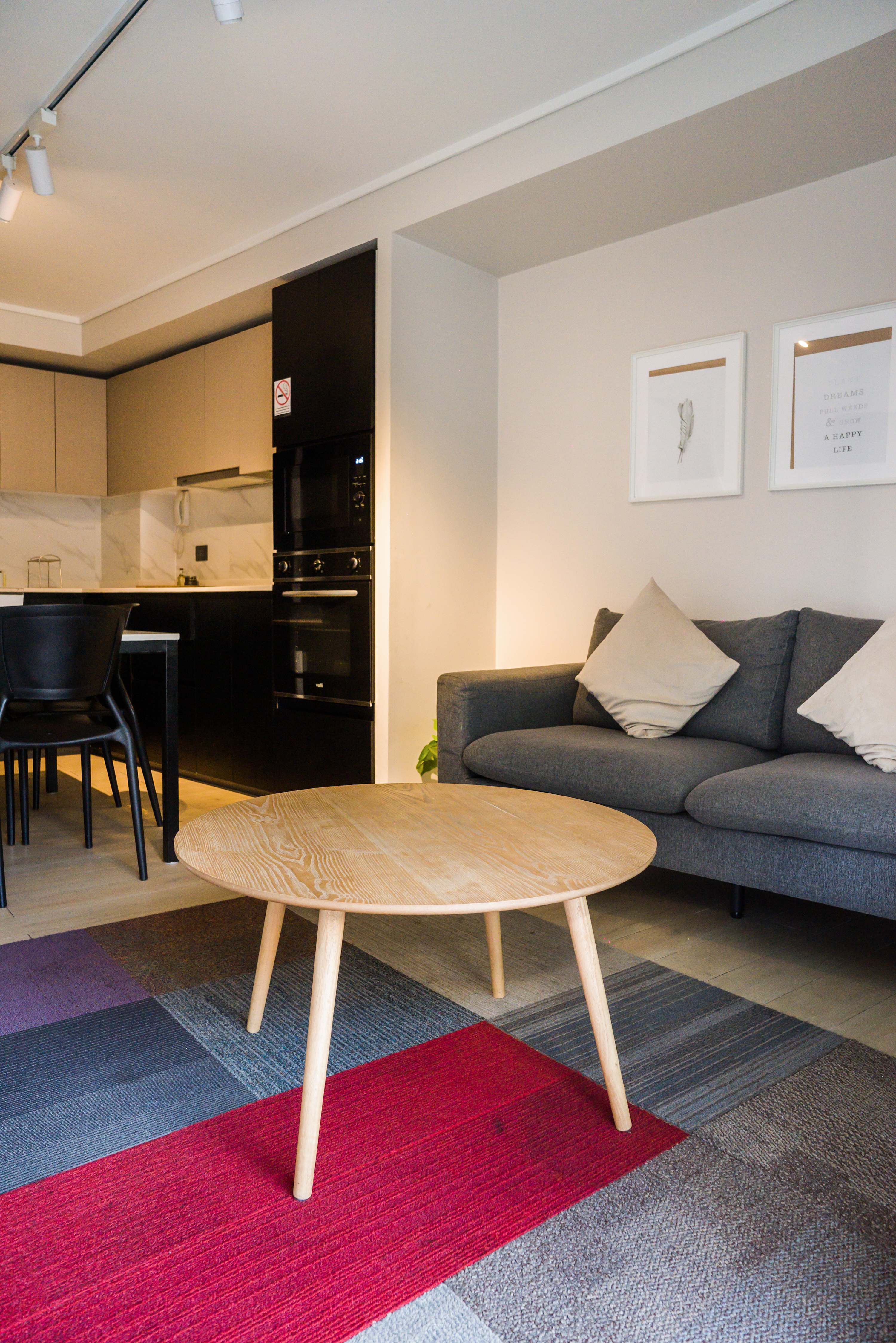Relax in this chic studio's cozy living area with modern decor and a sleek kitchen, perfect for a stylish urban retreat.
