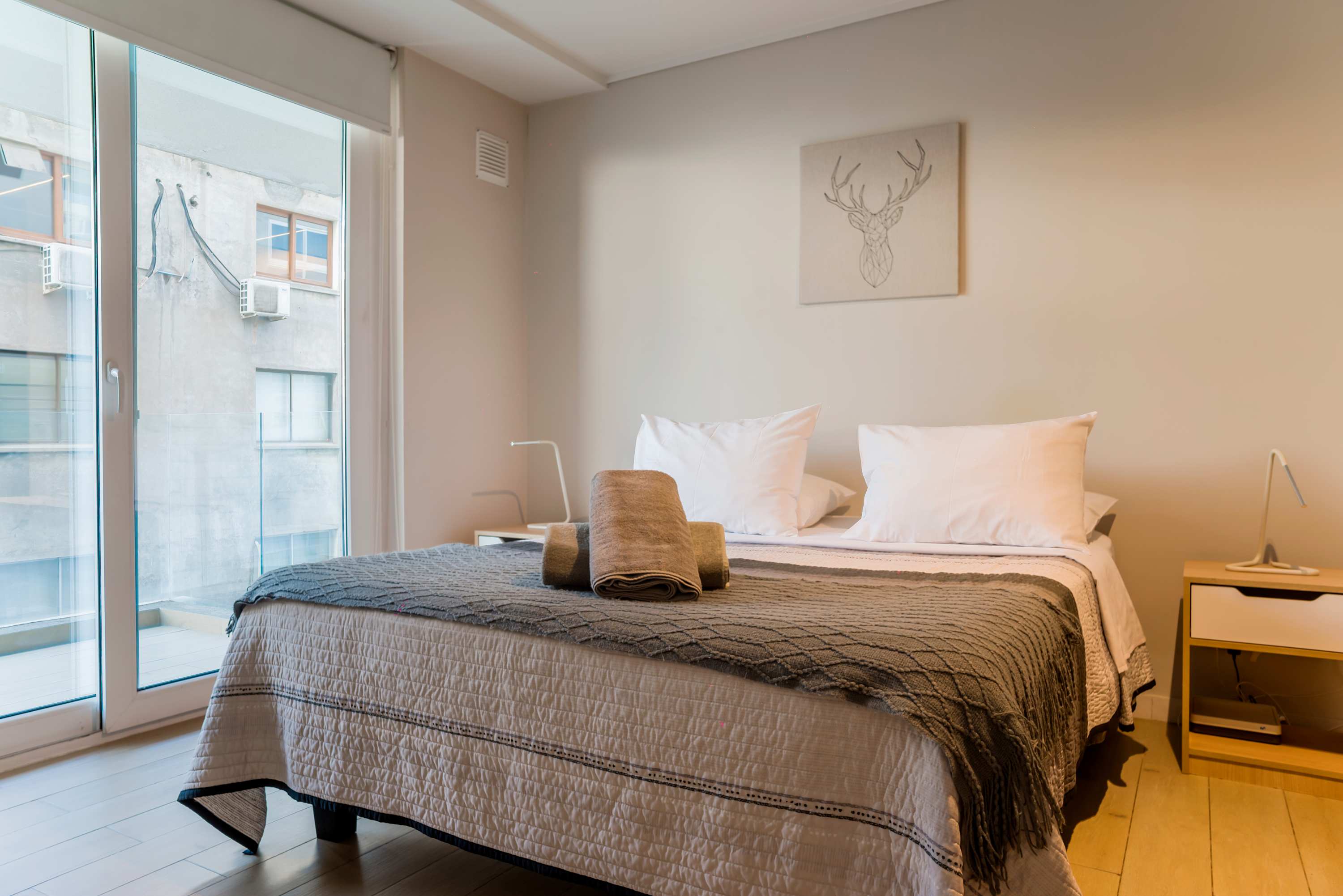 Cozy bedroom with plush bedding and natural light from the balcony, perfect for a peaceful retreat.