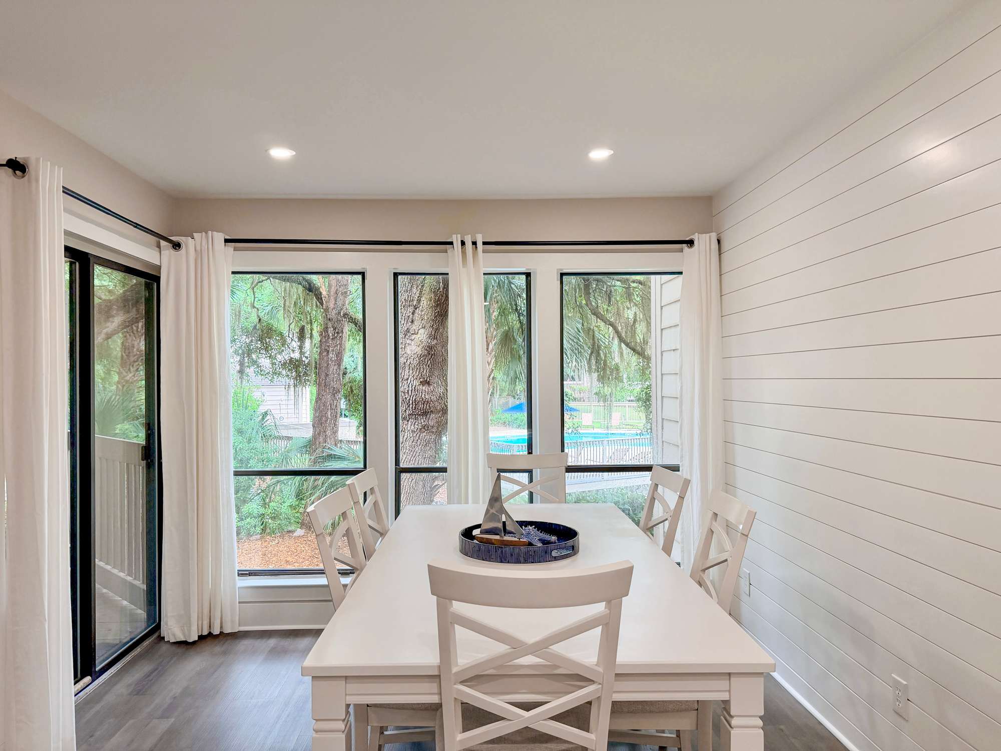 Gather around this inviting dining table where natural light streams through expansive windows, creating the perfect setting for memorable meals with loved ones.