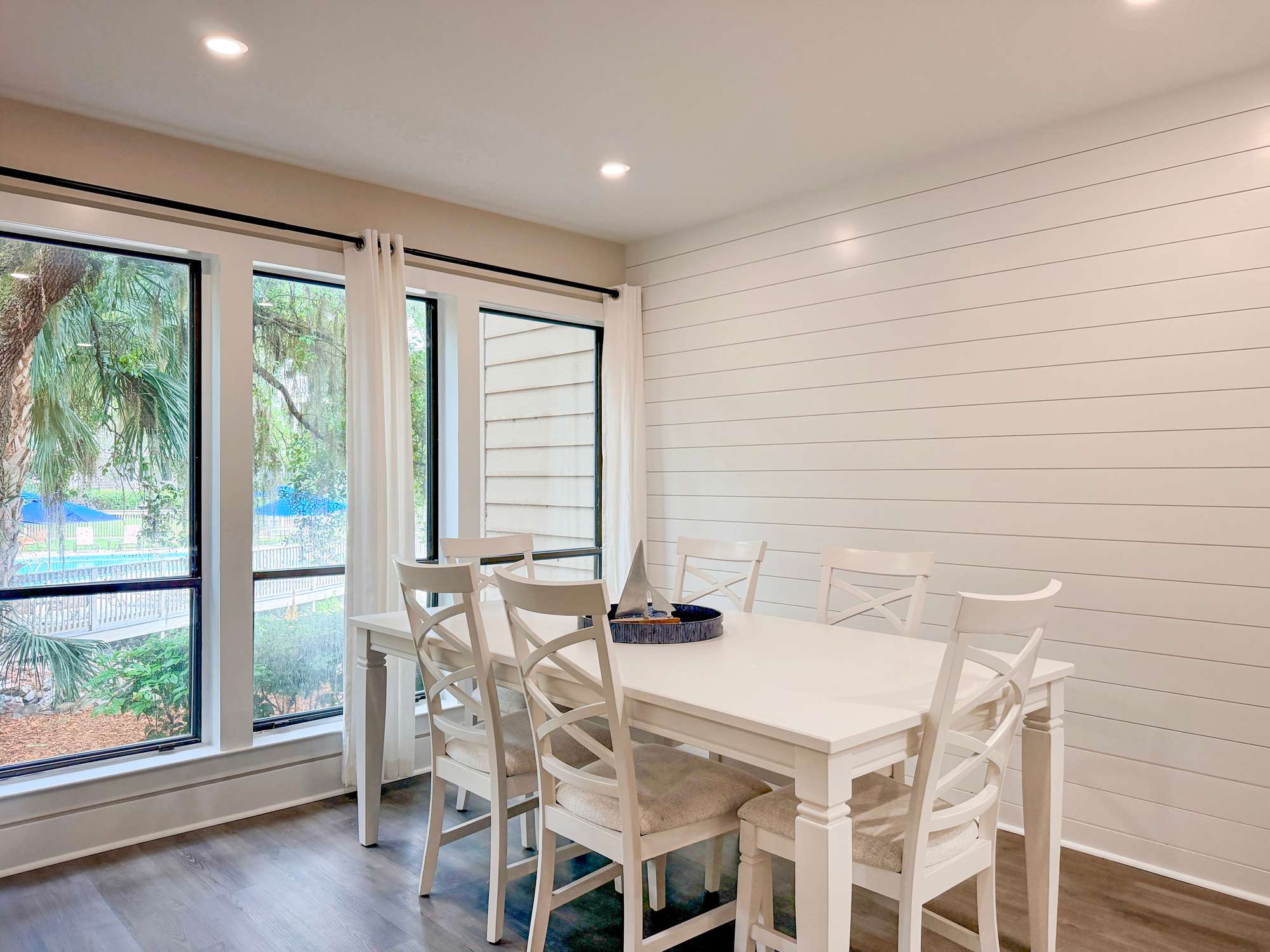 Gather around this inviting dining table where natural light streams through expansive windows, creating the perfect setting for memorable meals with loved ones.