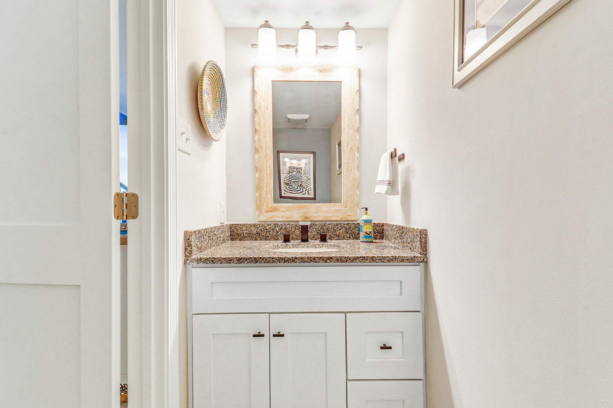 A convenient half bath on the main level for guests to freshen up without heading upstairs. White shaker vanity, granite counter, and a decorative mirror keep it polished and functional.
