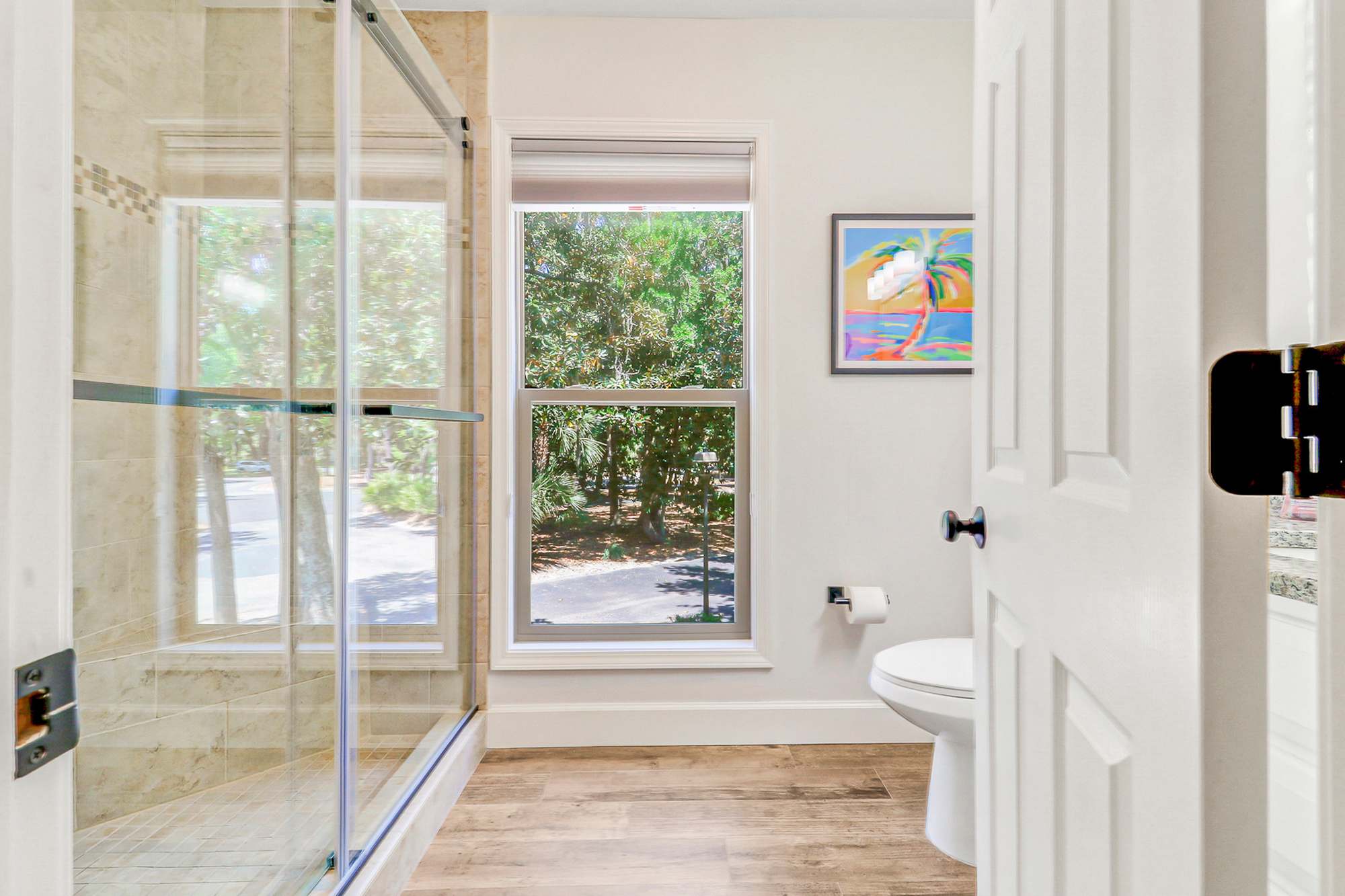 The private en-suite bath offers a large glass-enclosed tiled shower with a tranquil tree-canopy view. A resort-quality experience guests will appreciate after a day at the beach.
