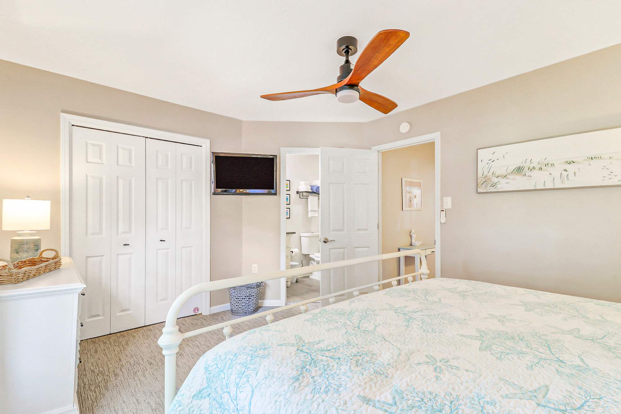 Second bedroom with a wall-mounted TV, double closet for guest storage, and private bath access. A comfortable, well-equipped room ideal for families or groups sharing the home.