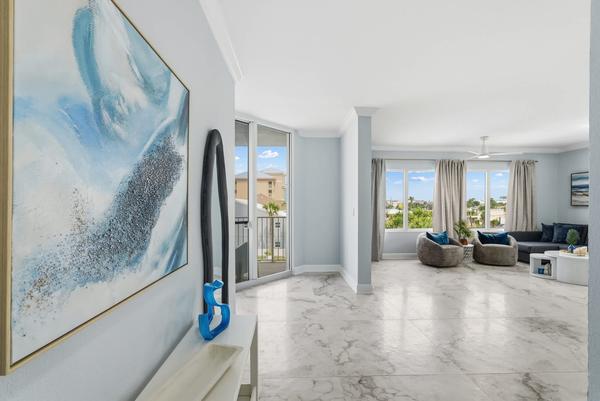Tidewater 200 – Interior view of living room with grey furniture, large windows, and marble flooring.