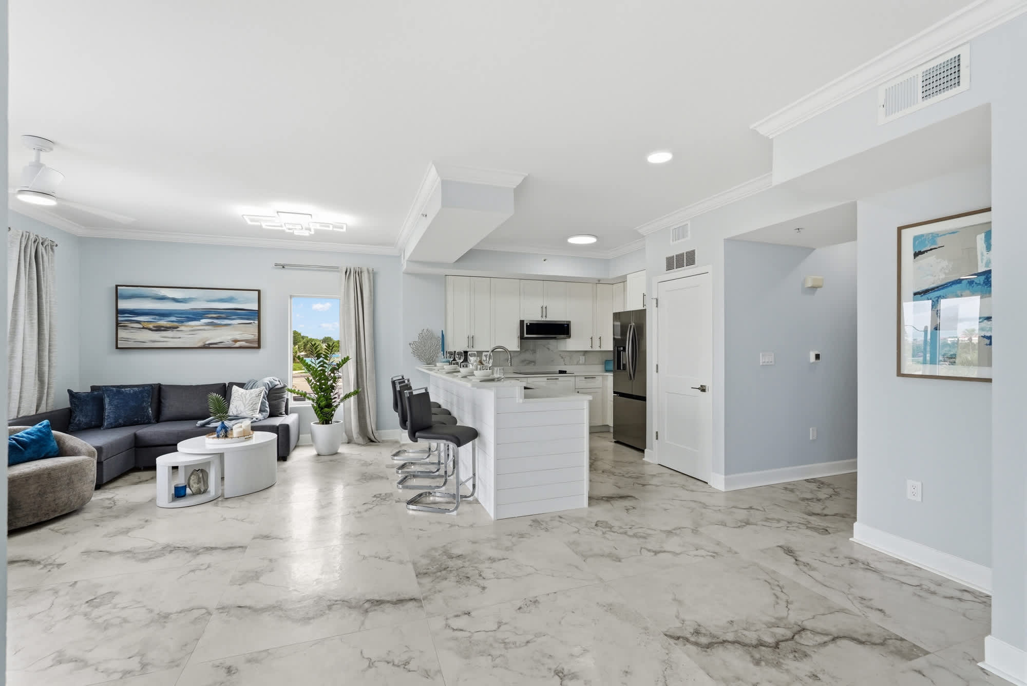 Tidewater 200 – Bright open-concept living area with gray sectional couch, island kitchen, and window view of greenery.