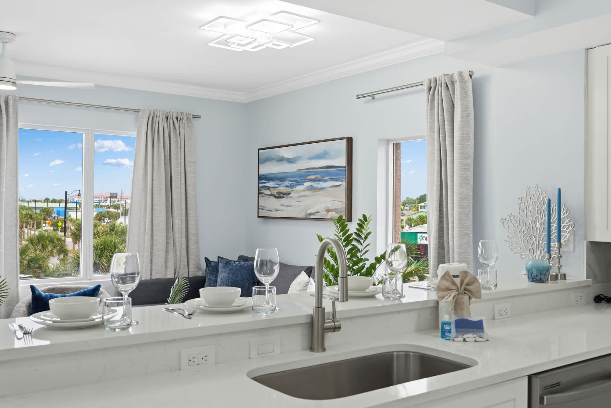 Tidewater 200 – Bright living area with a modern kitchen, large windows, and a view of palm trees and distant buildings.