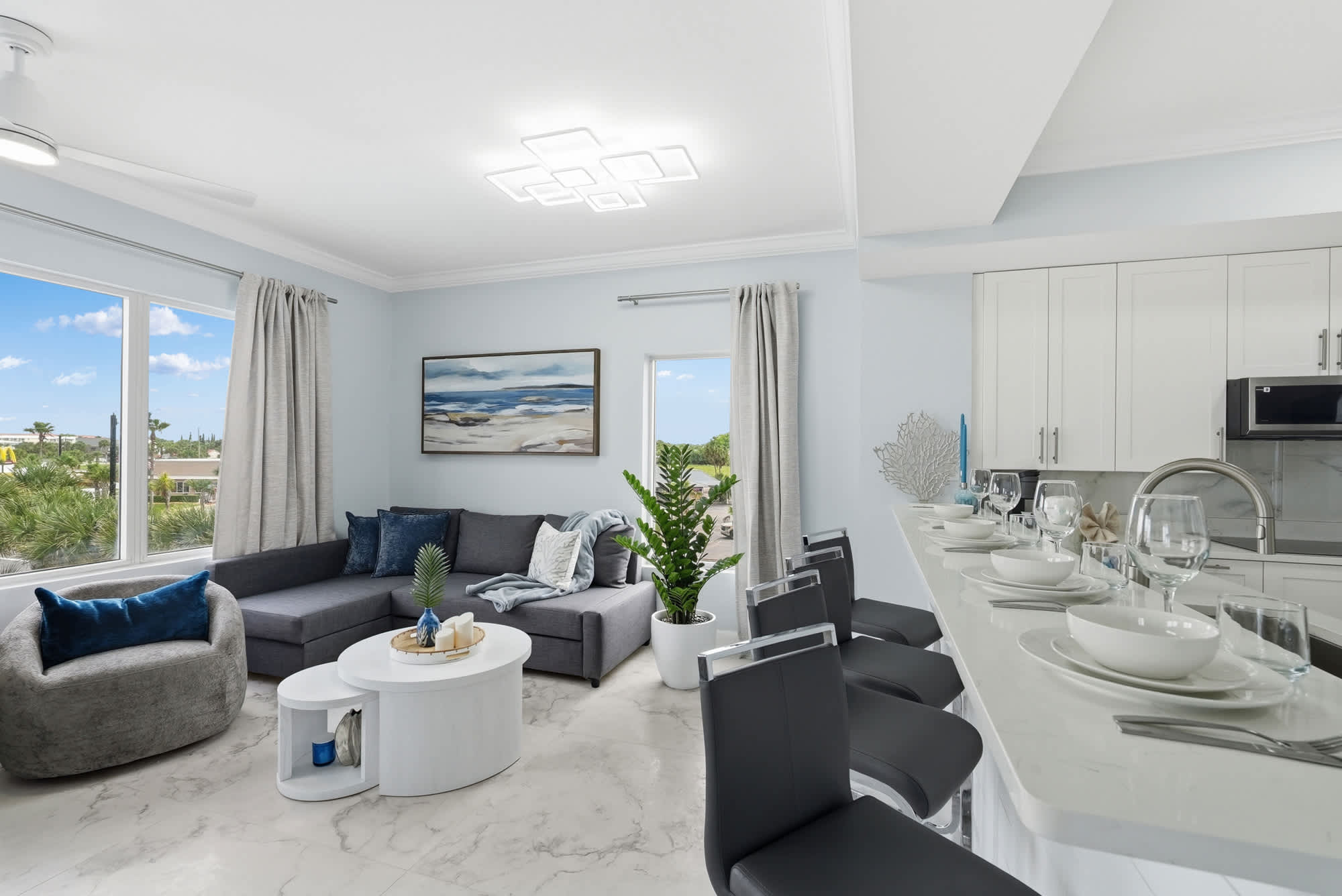 Tidewater 200 – Living room with sofa, armchair, dining bar, and kitchen view through large windows.