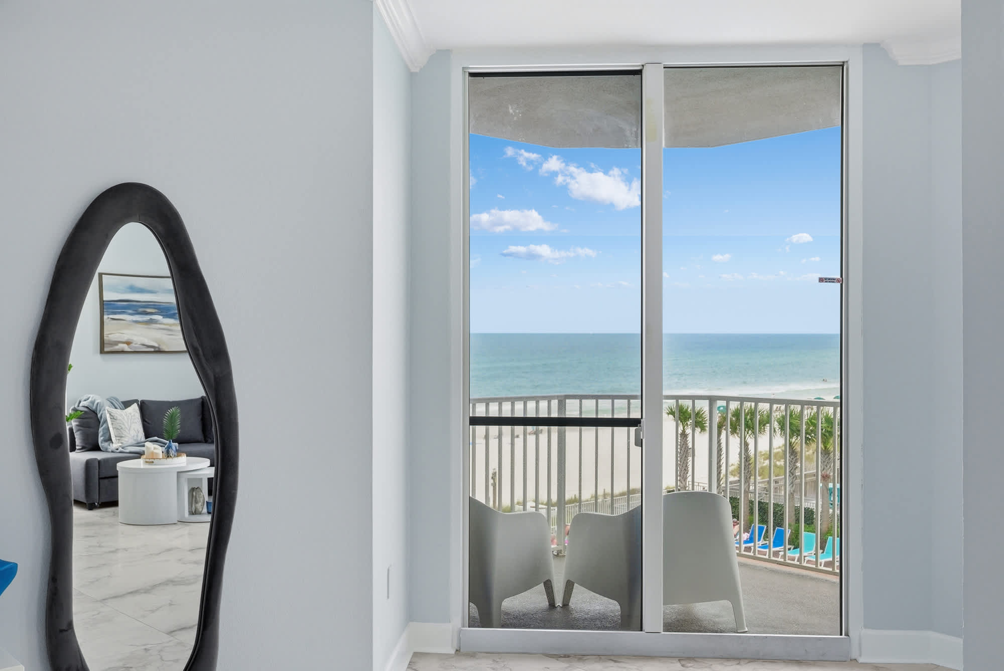 Tidewater 200 – Interior view of living area with balcony doors showcasing ocean view and outdoor seating.