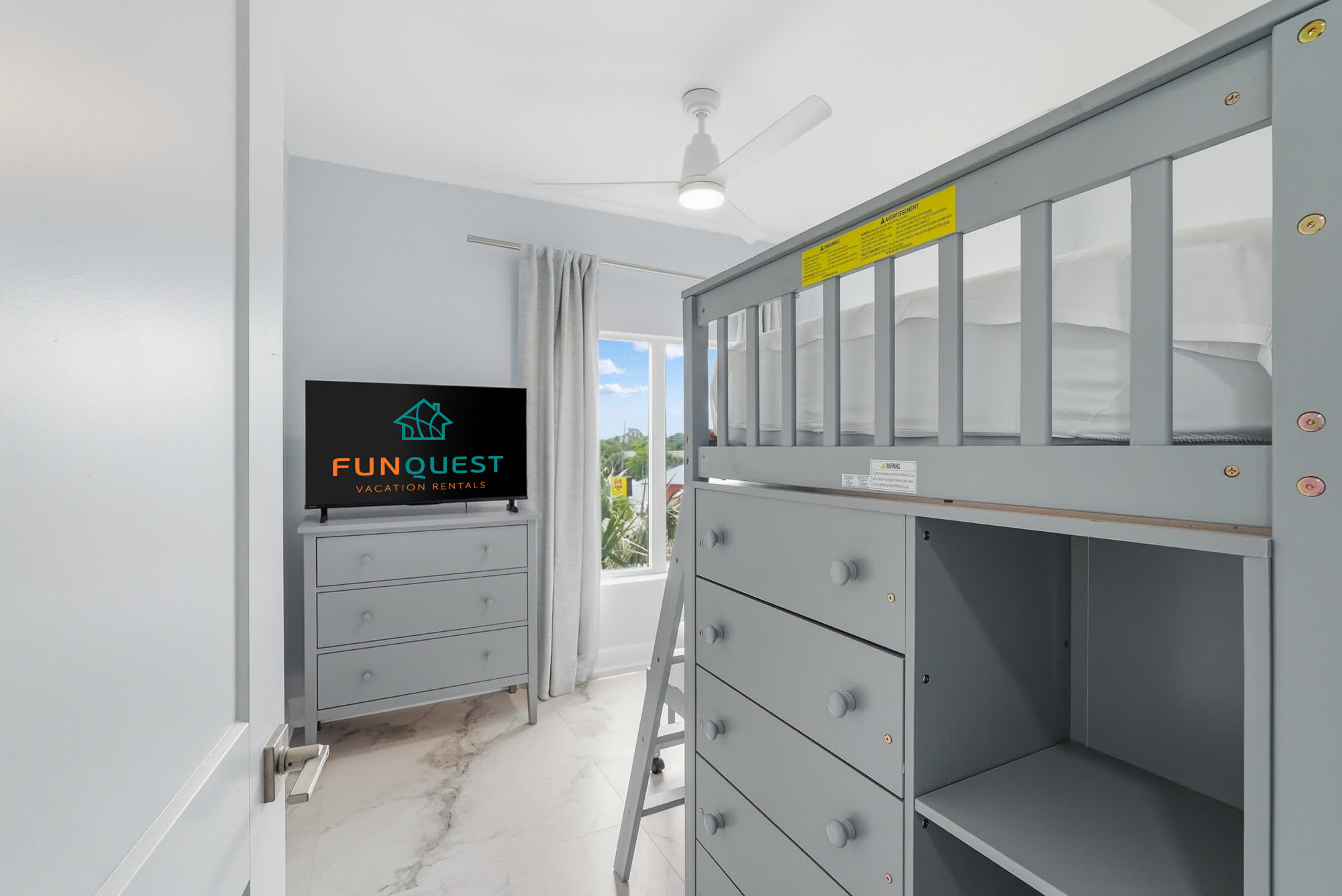 Tidewater 200 – Small bedroom with grey bunk bed, dresser, TV, and window showing outdoor view.