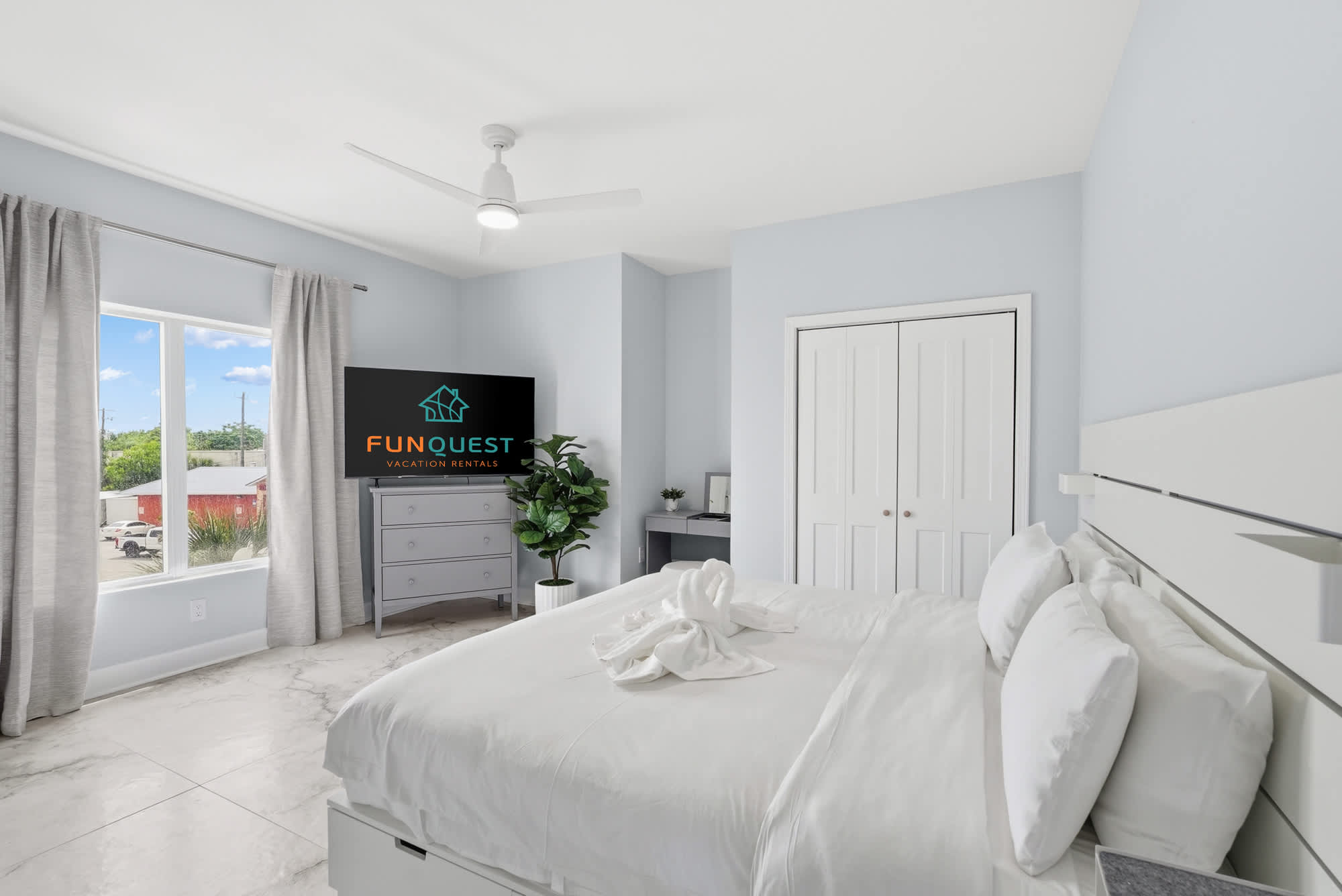 Tidewater 200 – Bright bedroom with a large window, a king-sized bed, and a TV, featuring light blue walls.