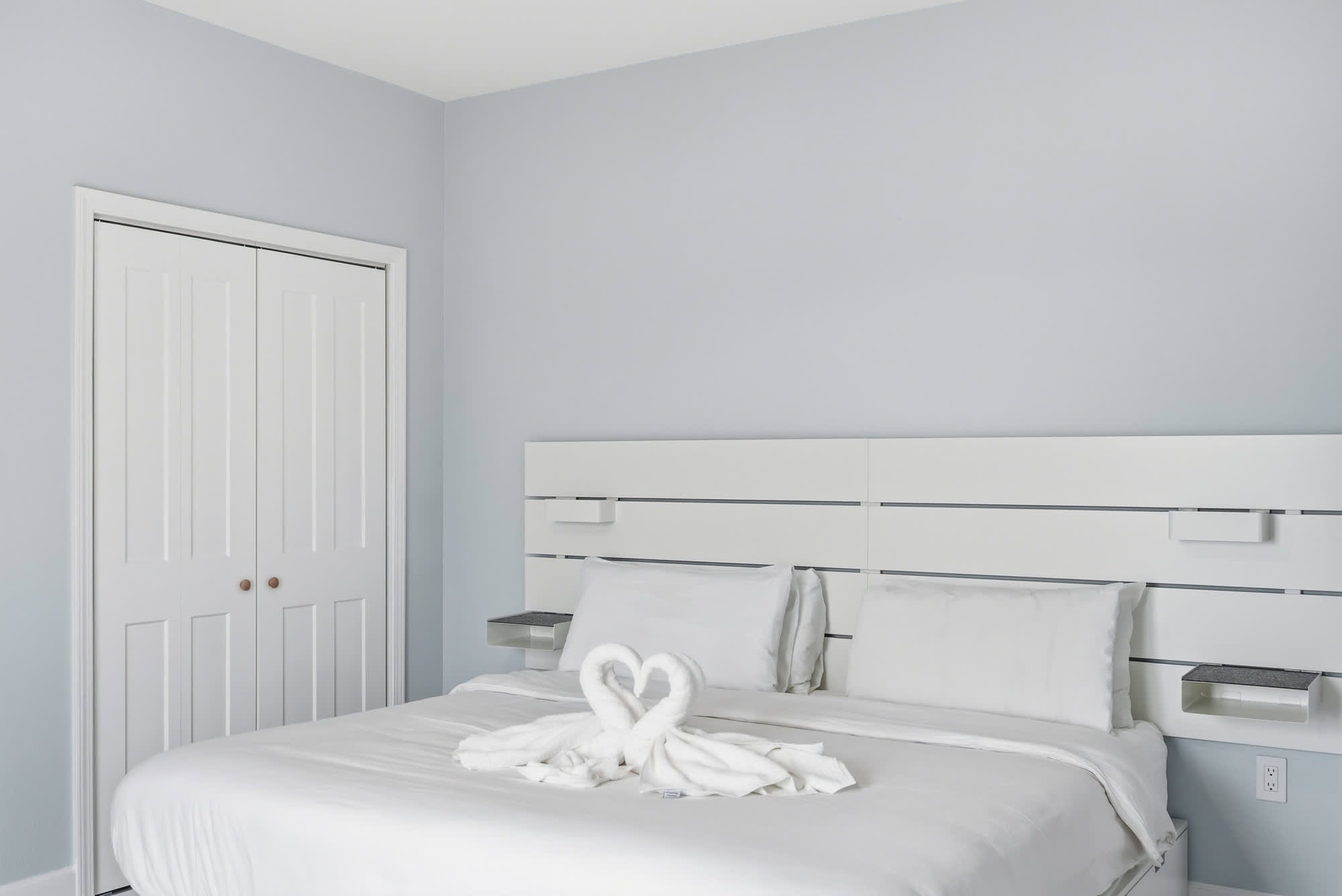 Tidewater 200 – Sleek bedroom with a queen bed, white linens, and a towel swan sculpture.