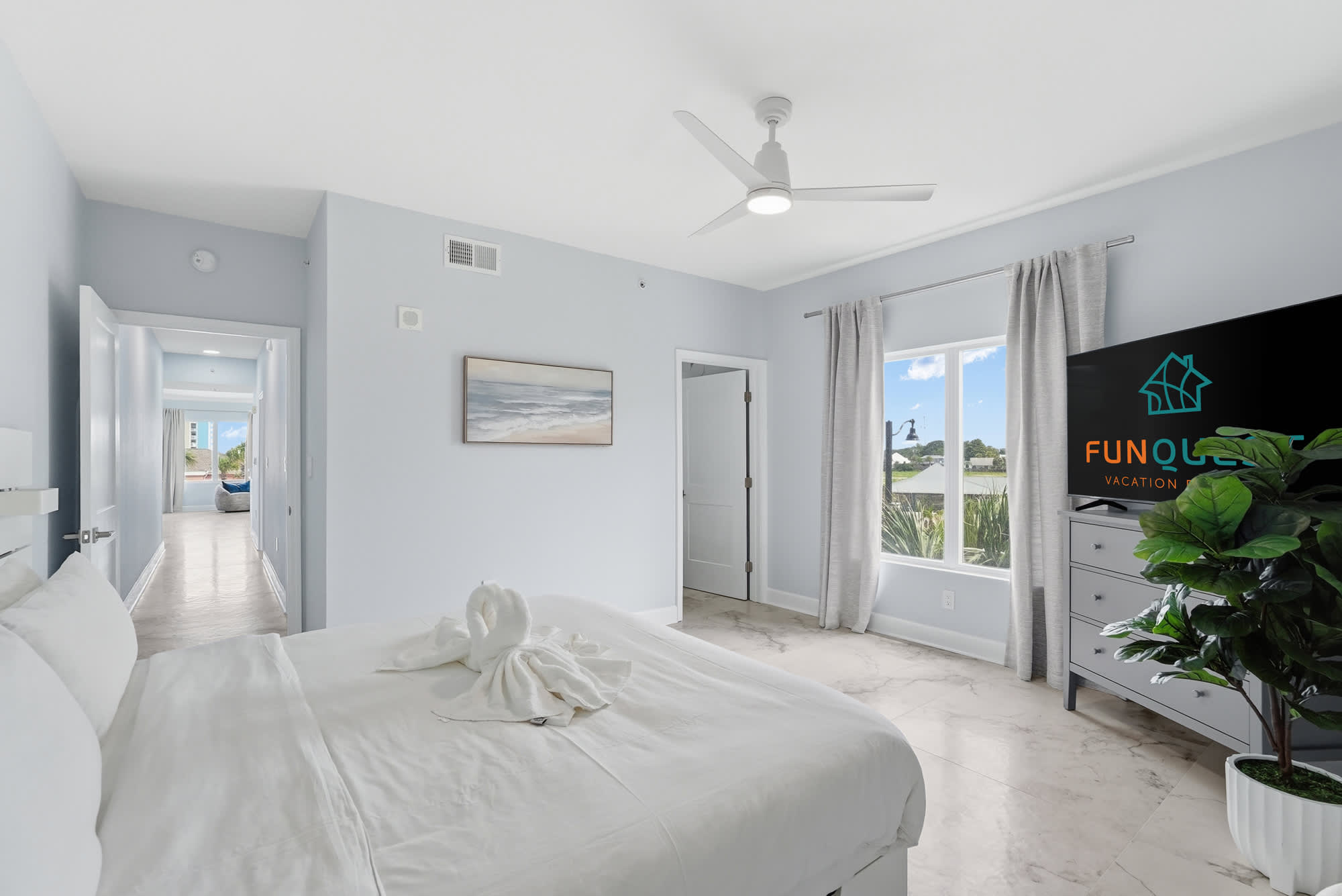 Tidewater 200 – Bright, modern bedroom with king bed, large window, dresser, and decorative towels shaped like swans.