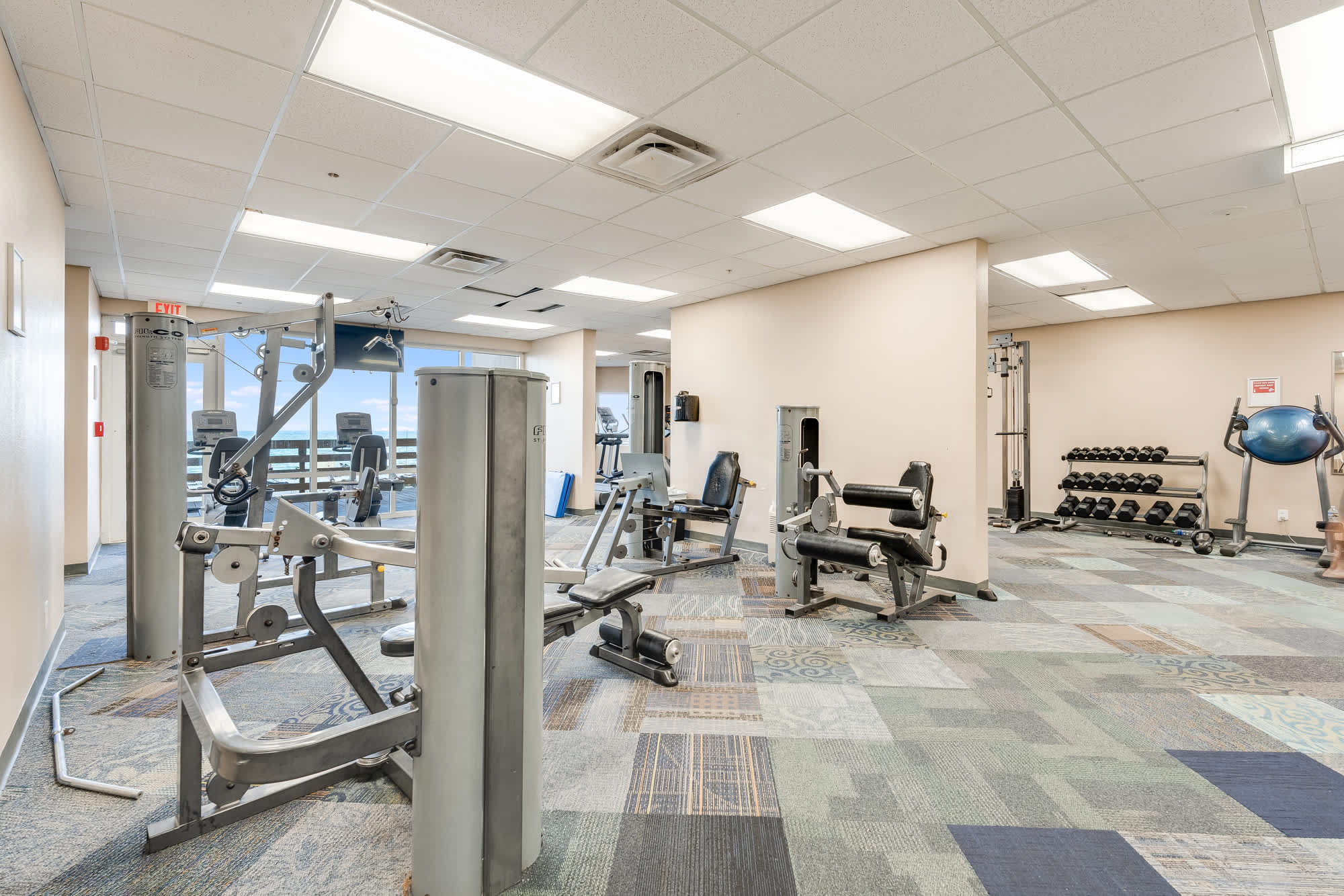 Tidewater 200 – Fitness center with weight machines, free weights, and large windows showing ocean views.