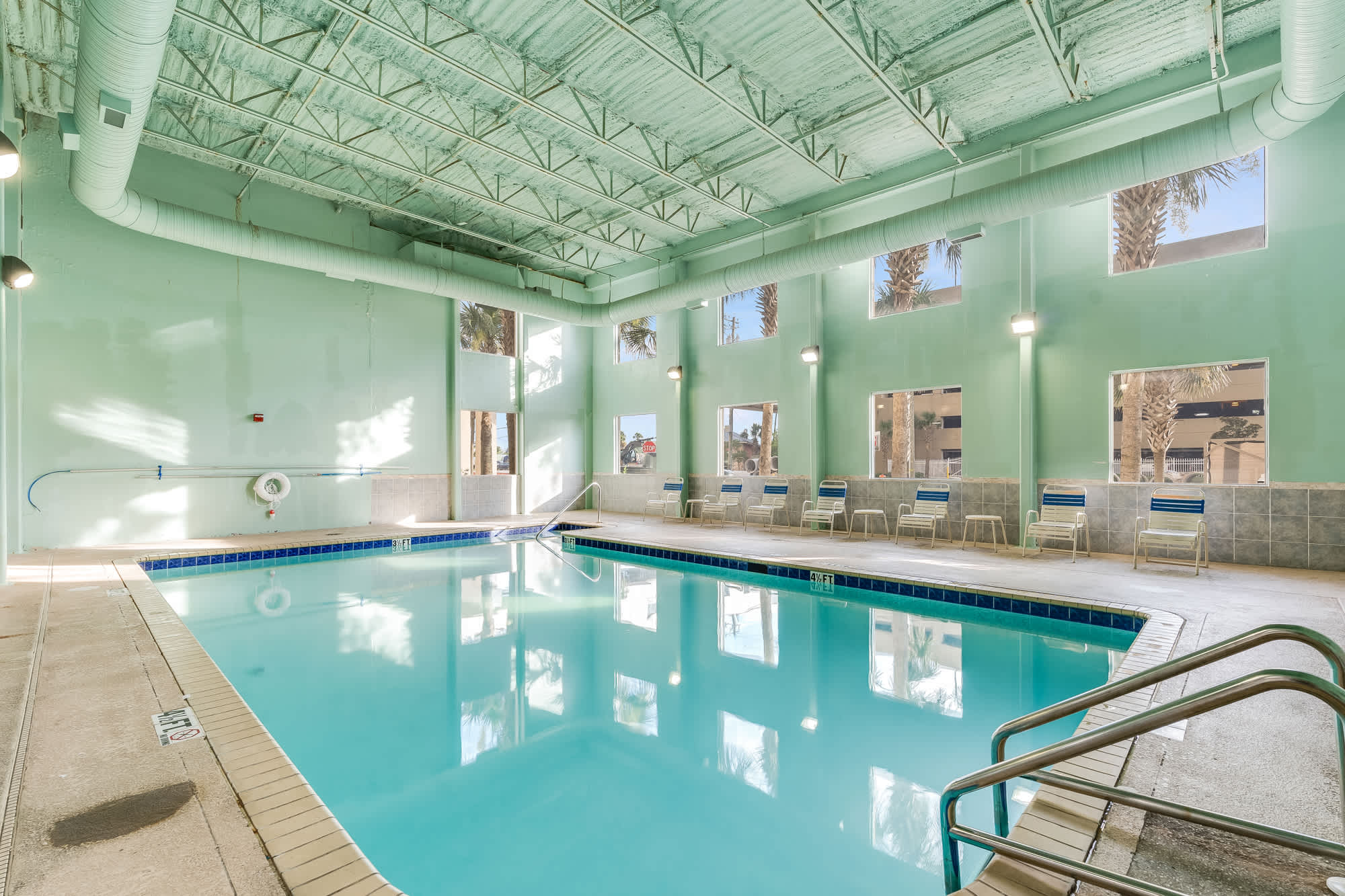 Tidewater 200 – Indoor pool area with large windows, green walls, and poolside seating.