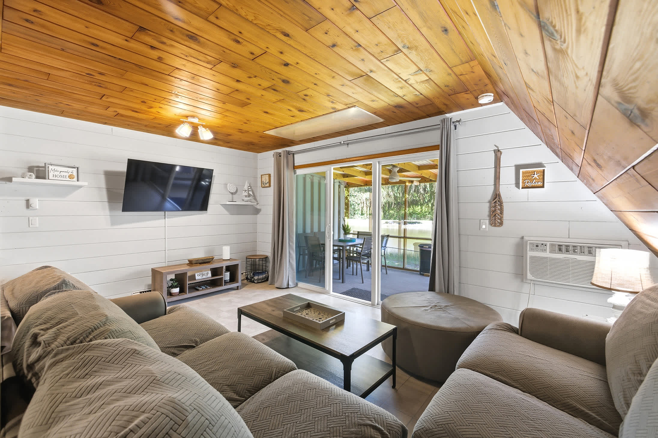 Living room includes a wall-mounted TV and direct deck access — easy to move between inside and out.