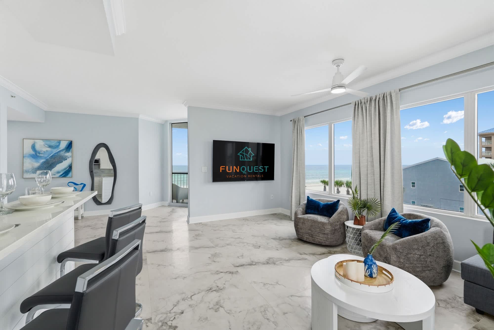 Tidewater 200 – Bright living area with ocean view, modern furniture, and a large TV.