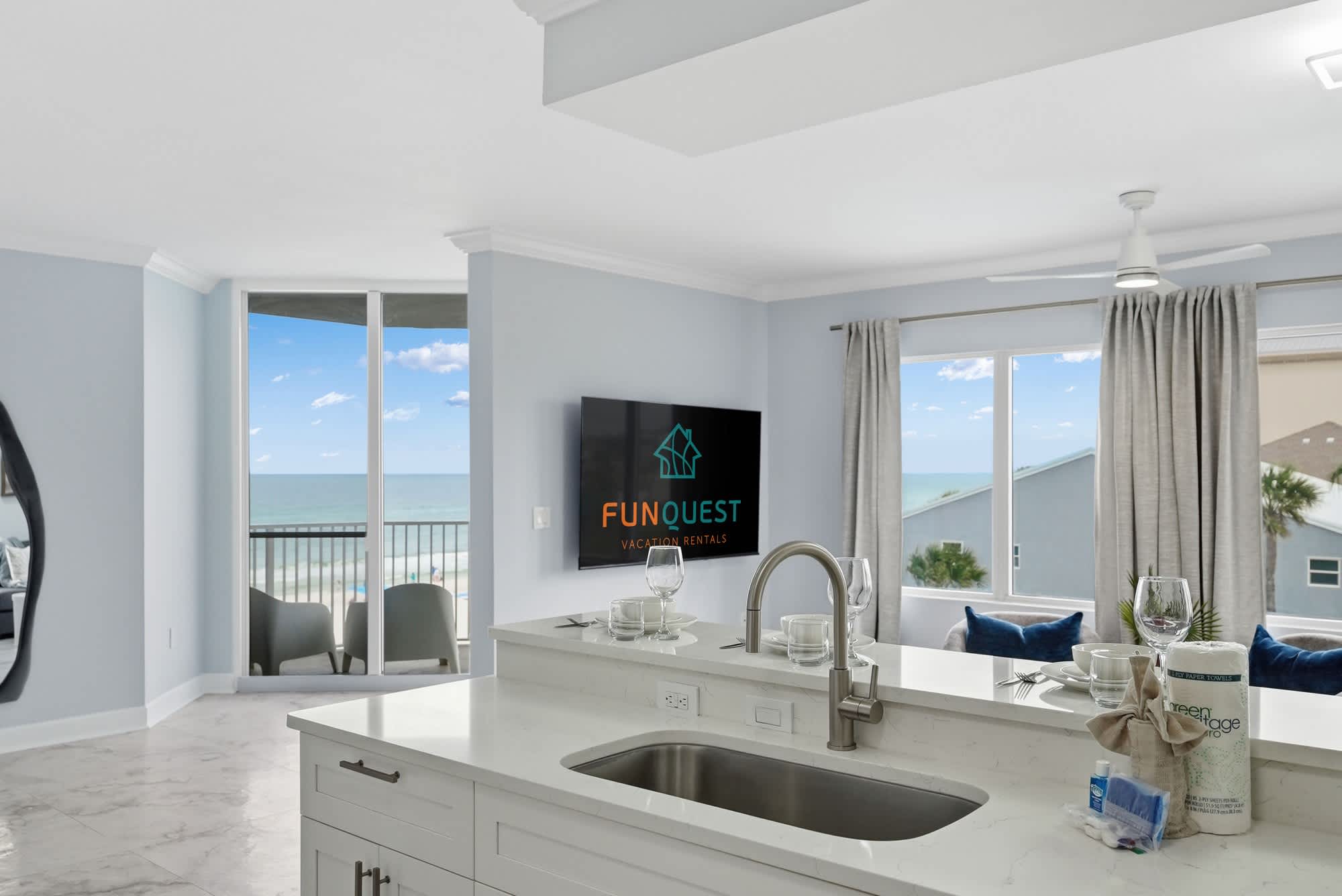 Tidewater 200 – Bright living area with ocean view, modern kitchen island, and sliding glass doors to a balcony.