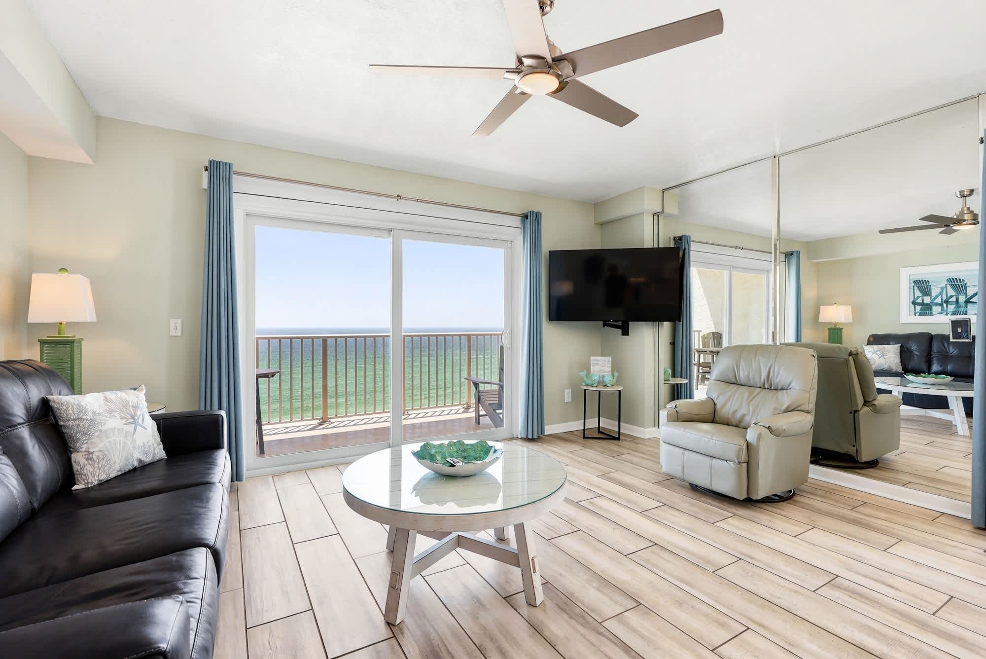 The Summit 1101 – Living room with ocean view, sliding glass doors, leather sofa, glass coffee table, and TV.